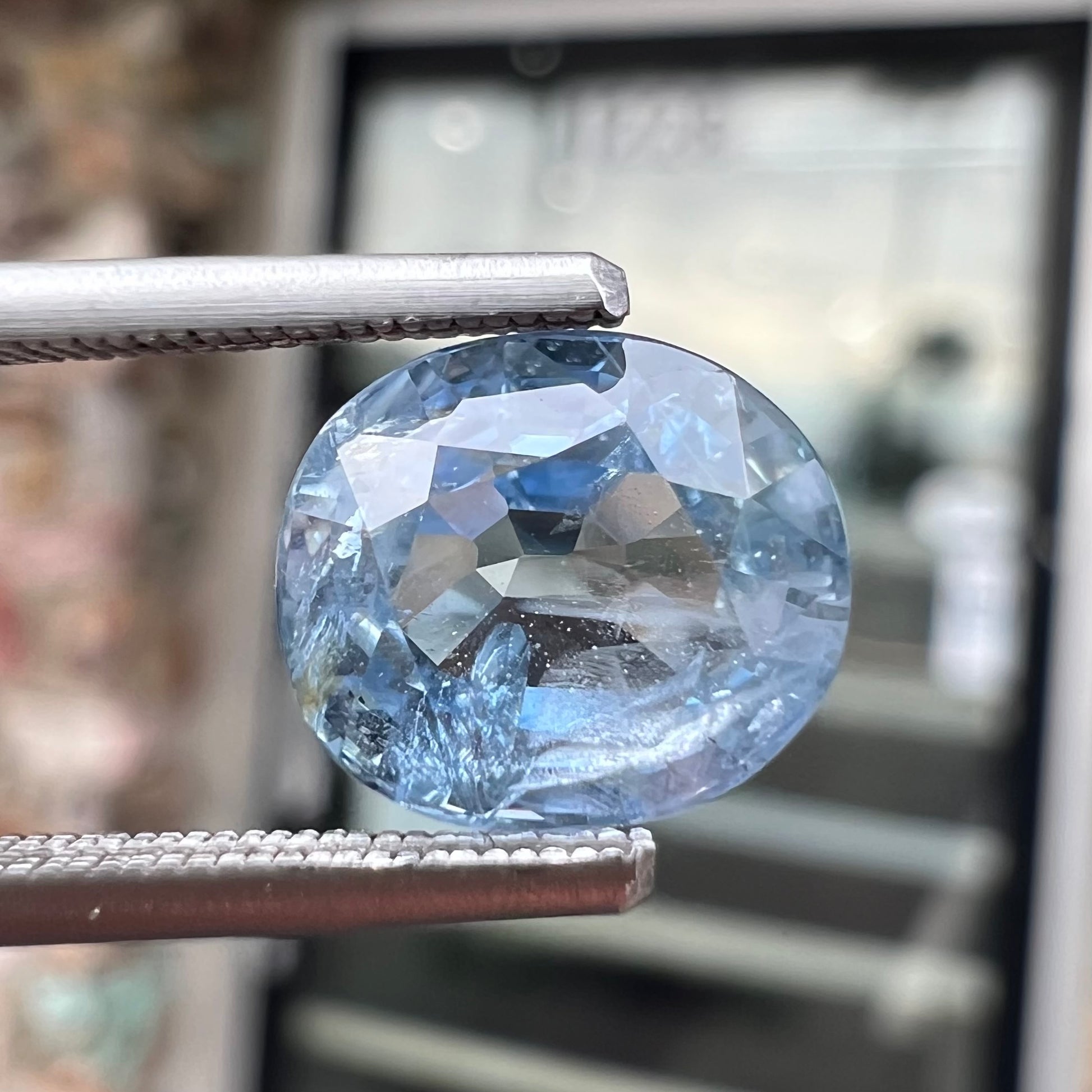 A loose, faceted oval cut light blue natural sapphire gemstone.
