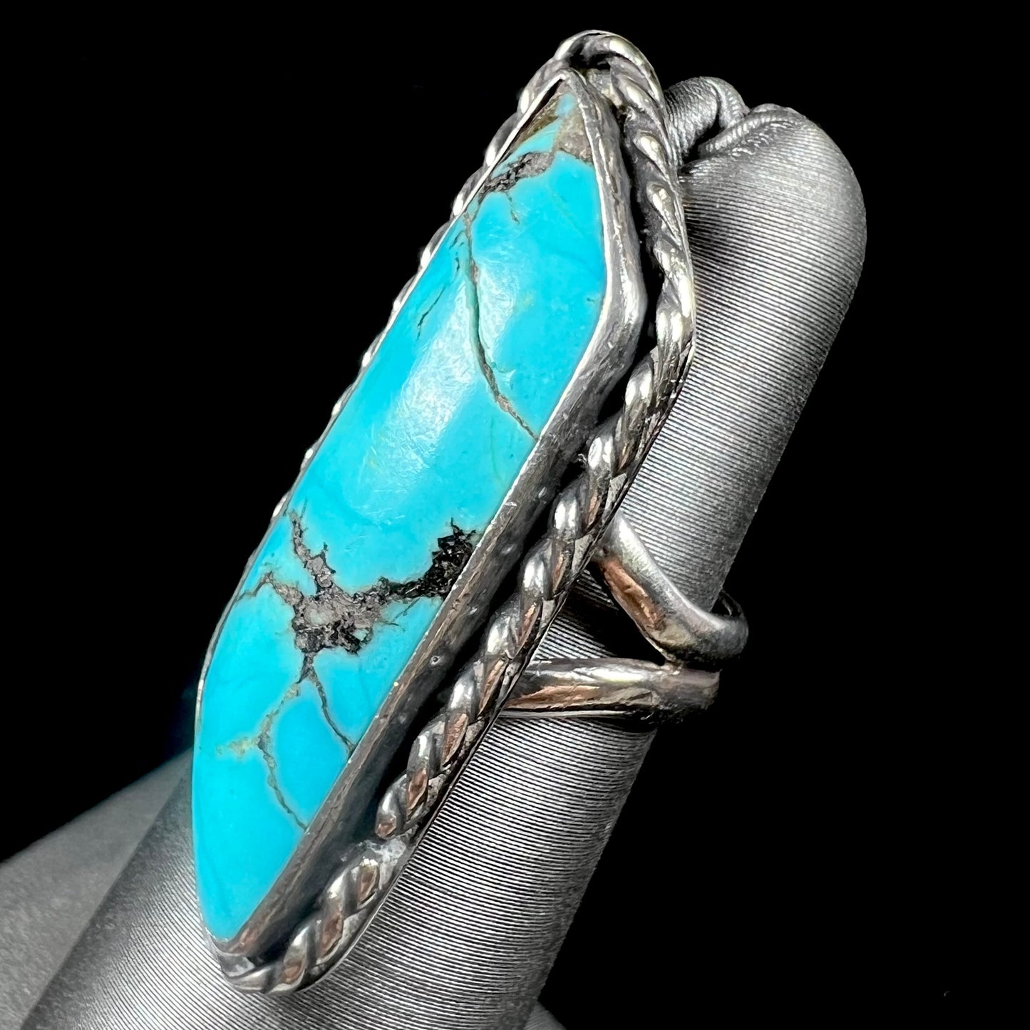 A vintage, Southwest style sterling silver ring set with a natural turquoise stone. The stone is blue with a black matrix.