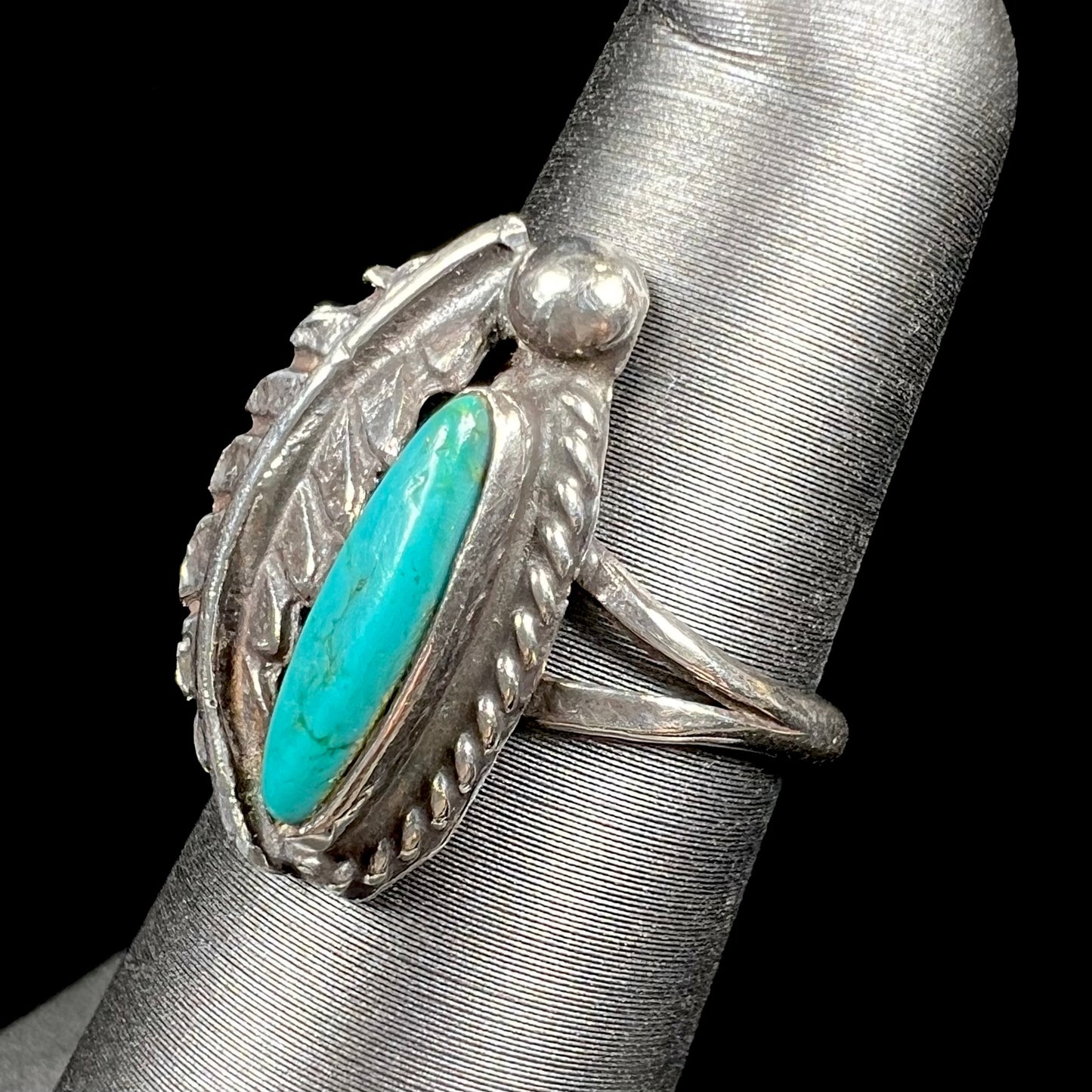 A ladies' sterling silver feather style ring set with a marquise cut turquoise stone.