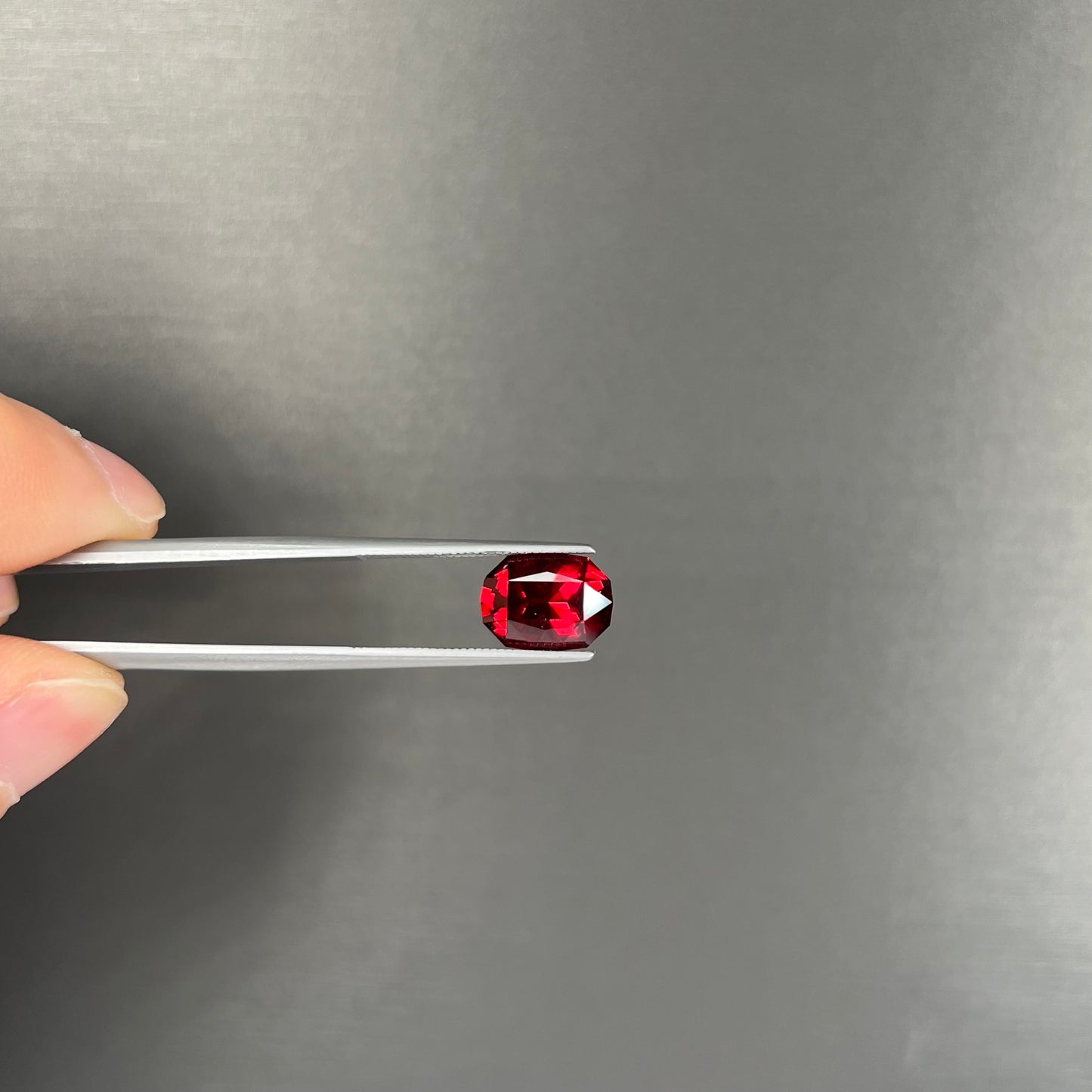 A loose, octagon cut rhodolite garnet gemstone. The stone is a deep, purplish crimson red color.