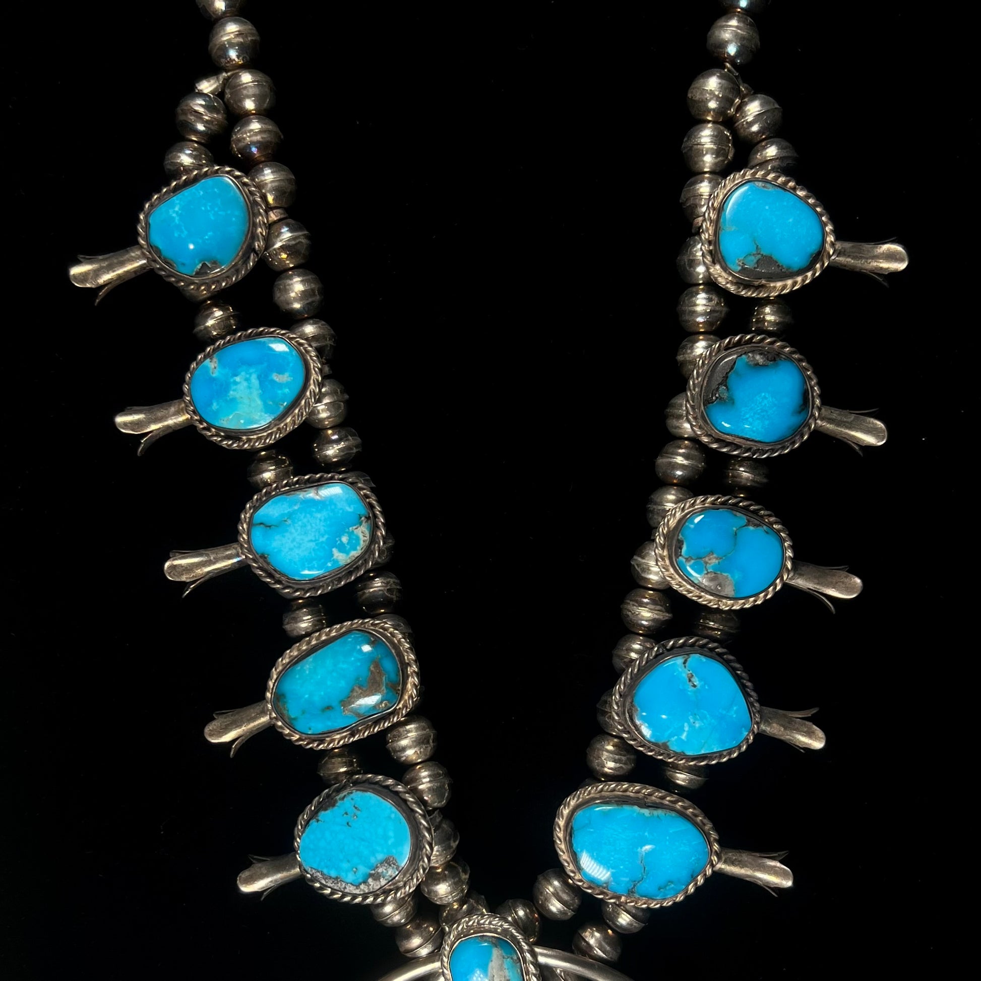 A vintage Navajo squash blossom necklace set with blue Kingman turquoise stones.