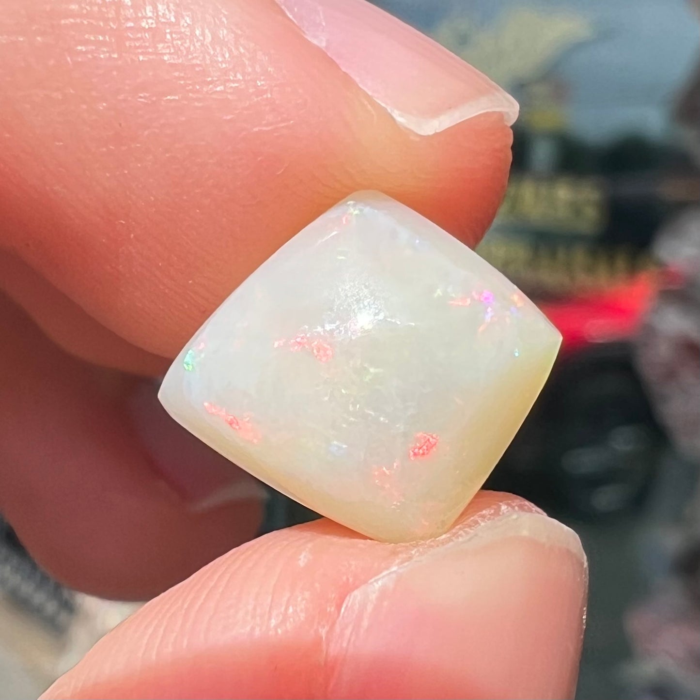 A loose, kite shaped white opal stone from Coober Pedy, Australia. The stone has subdued red colors.