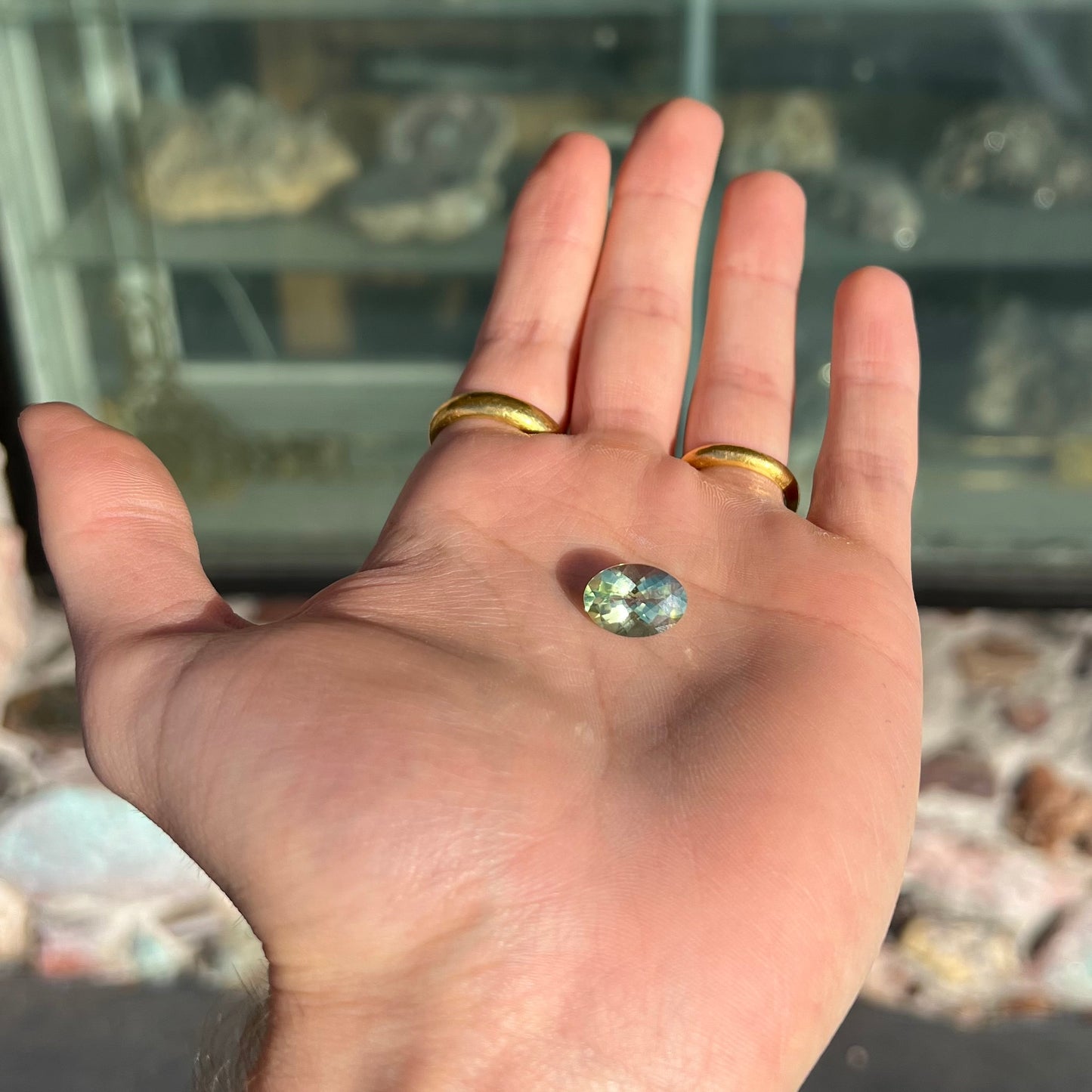 An oval checkerboard cut kiwi mystic topaz gemstone. The stone is a light yellowish green color.