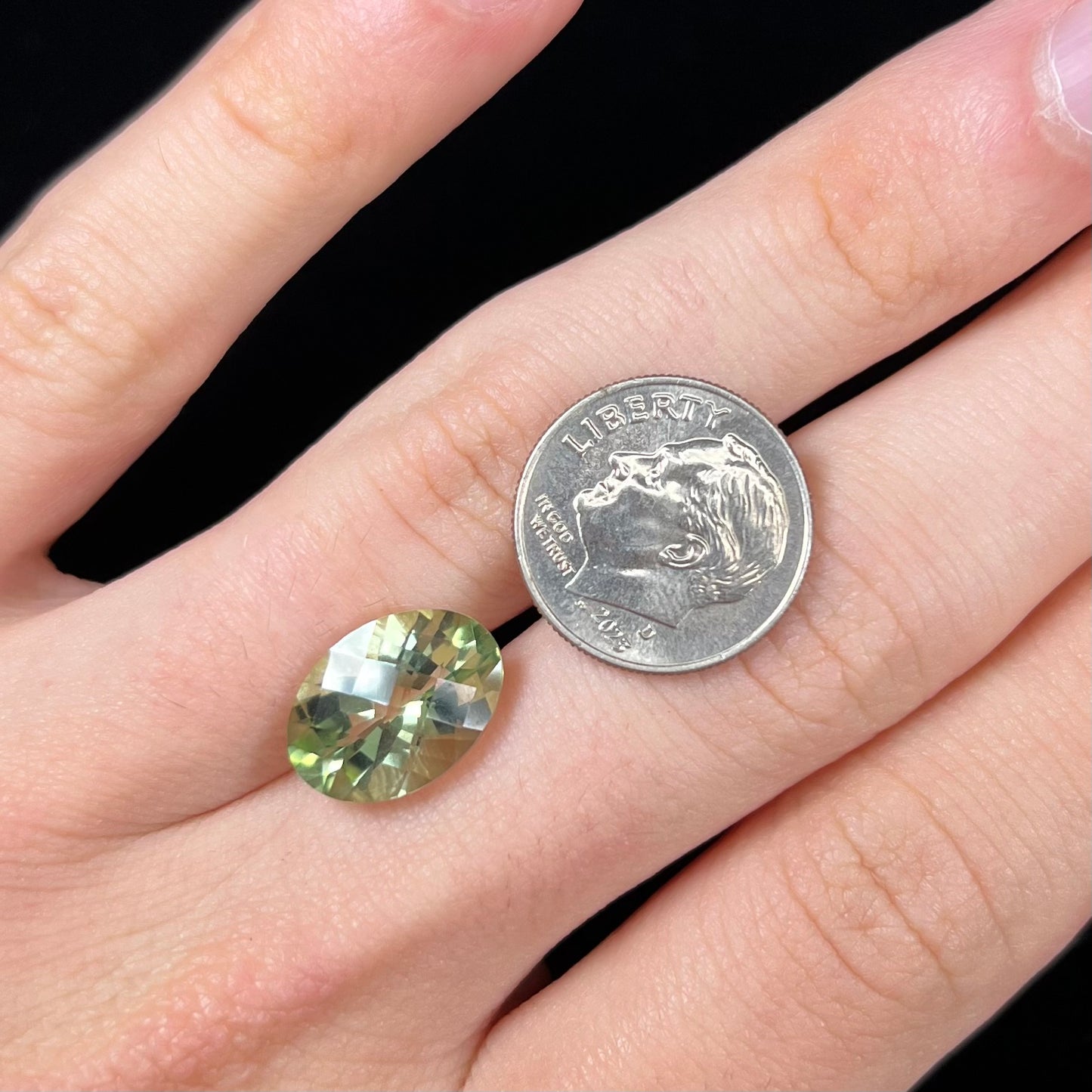 An oval checkerboard cut kiwi mystic topaz gemstone. The stone is a light yellowish green color.