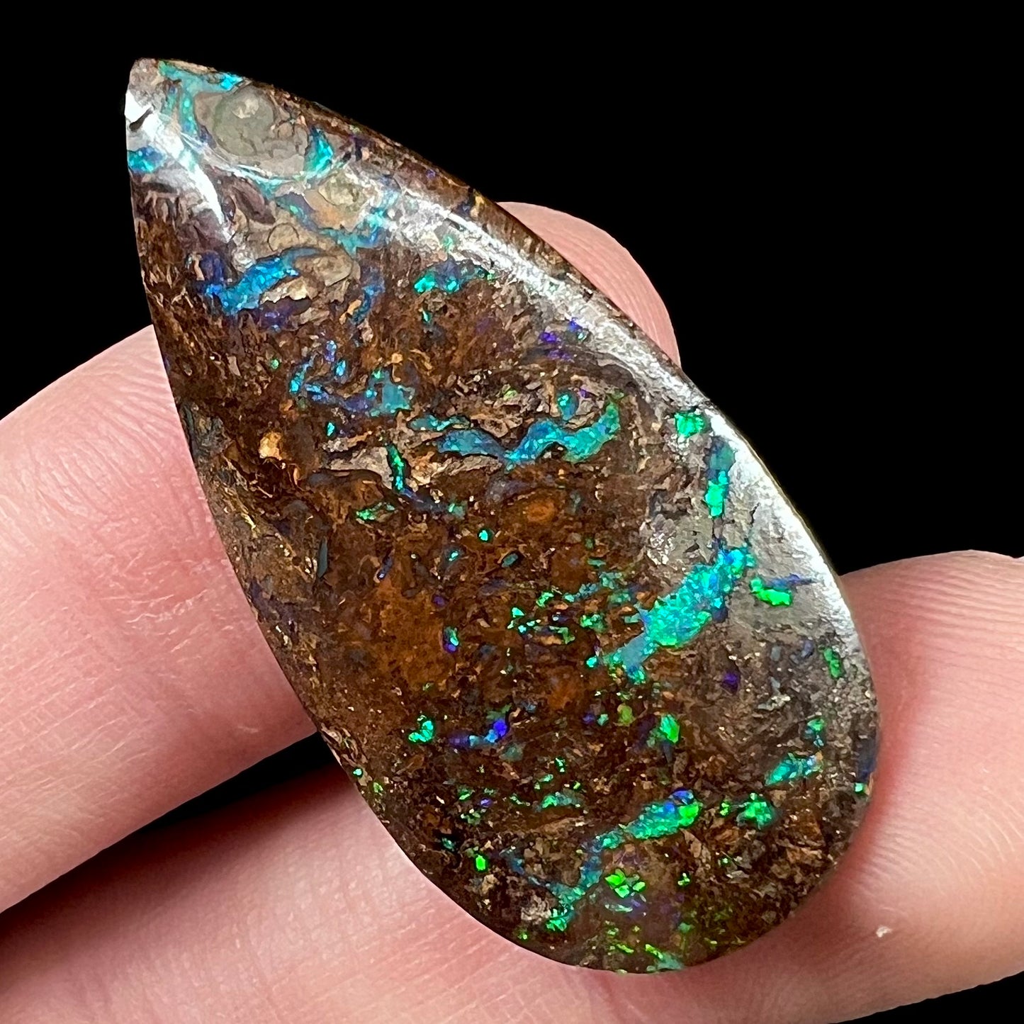 A pear shaped boulder opal stone from Koroit, Australia. The opal has blue and green flashes.