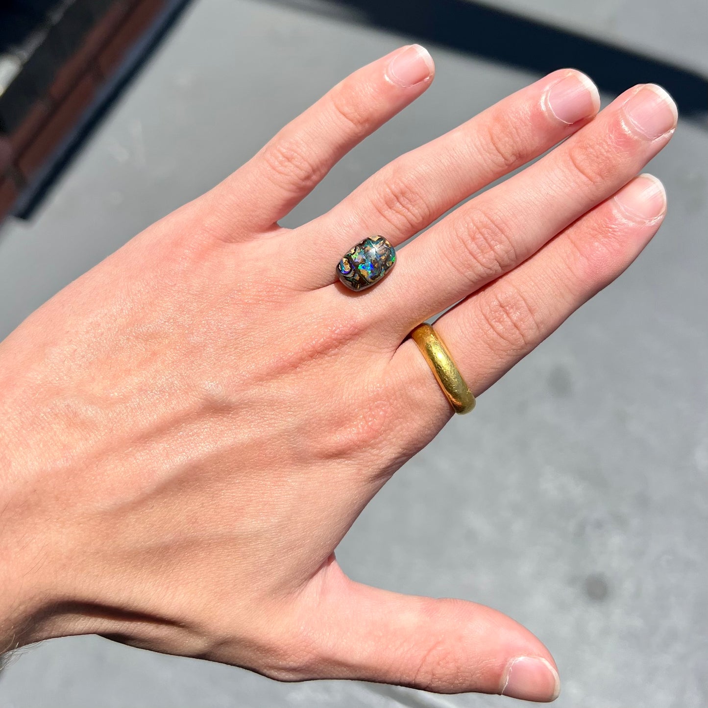 A loose, Koroit boulder opal stone. The opal plays bright blue and green colors on a patterned matrix.
