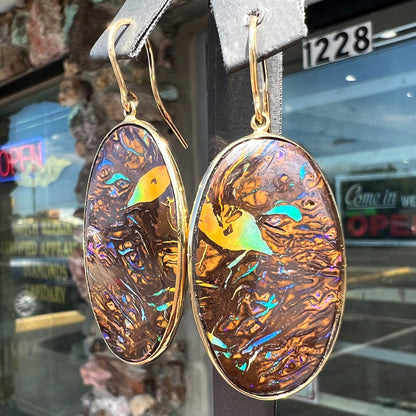 A pair of Koroit boulder opal dangle earrings set in yellow gold bezels.