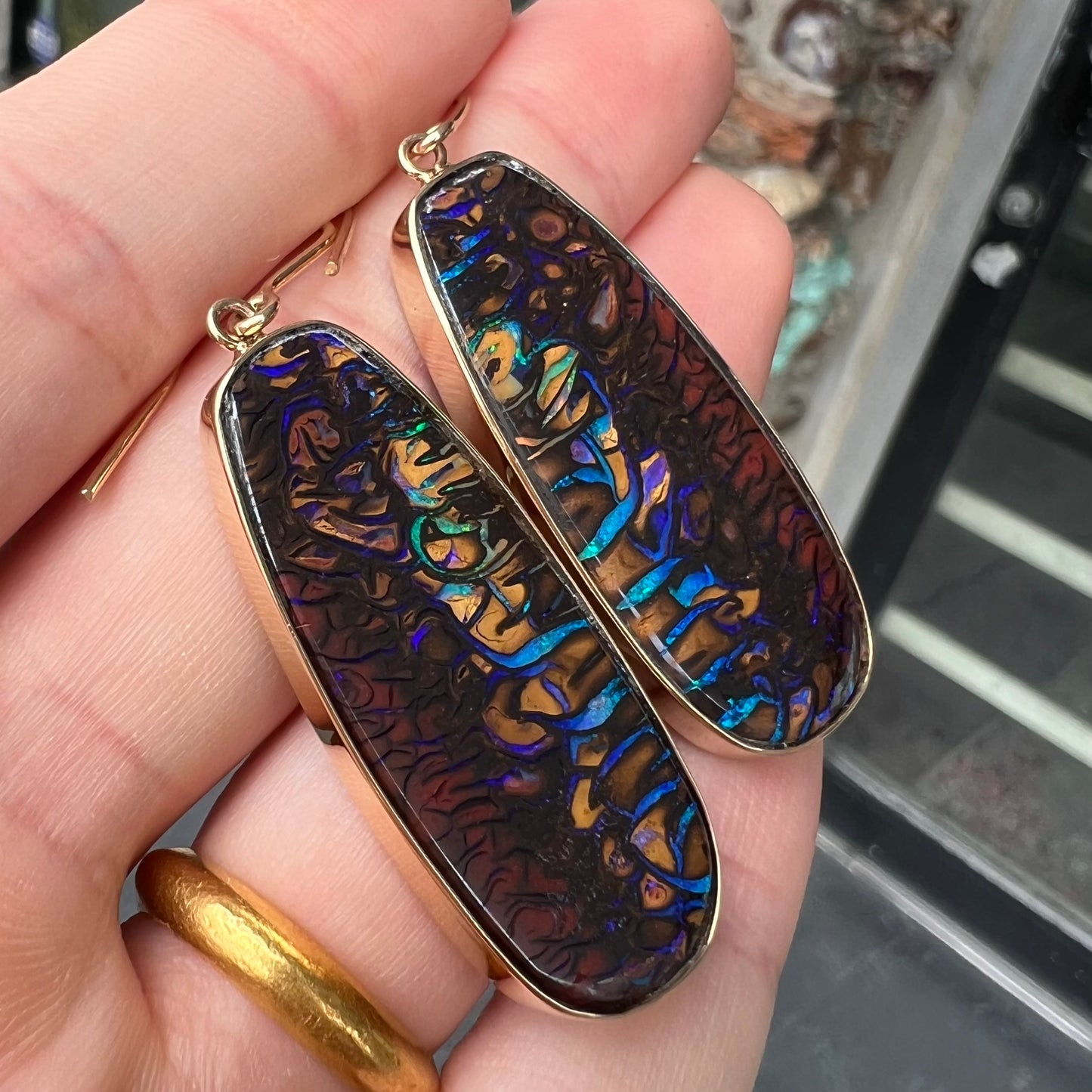 A matched pair of yellow gold patterned boulder opal dangle earrings. The opals are from Koroit, Australia.