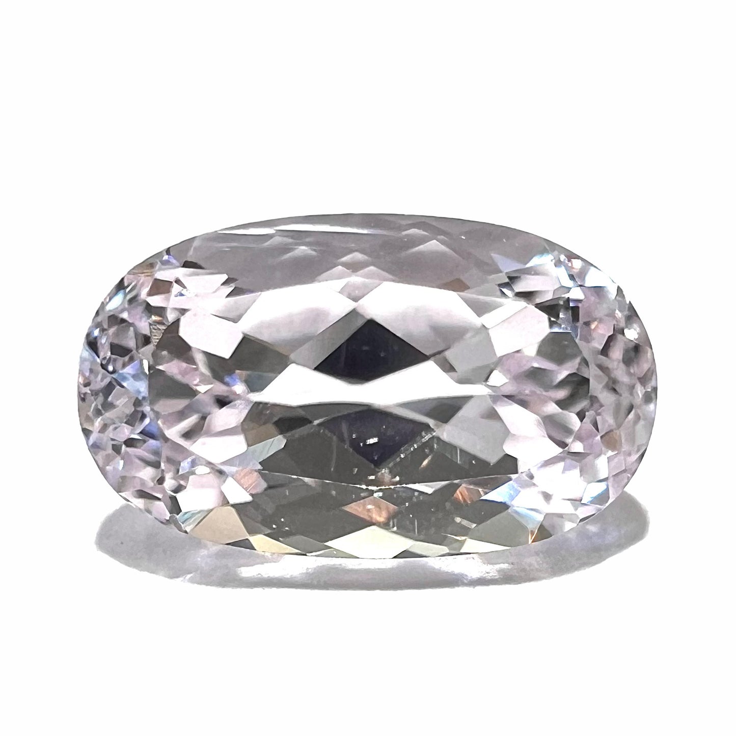 A loose, faceted oval cut kunzite gemstone. The stone is a light pink color.