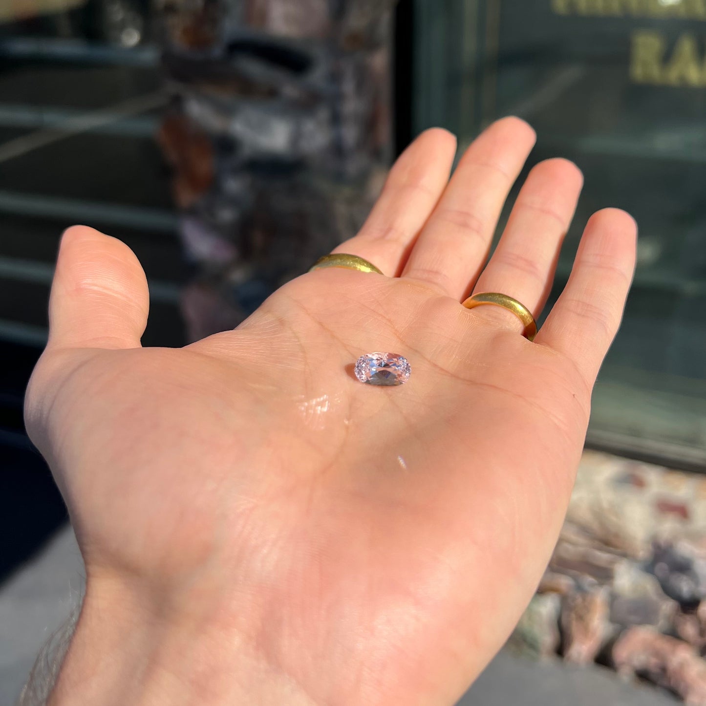 A loose, faceted oval cut kunzite gemstone. The stone is a light pink color.