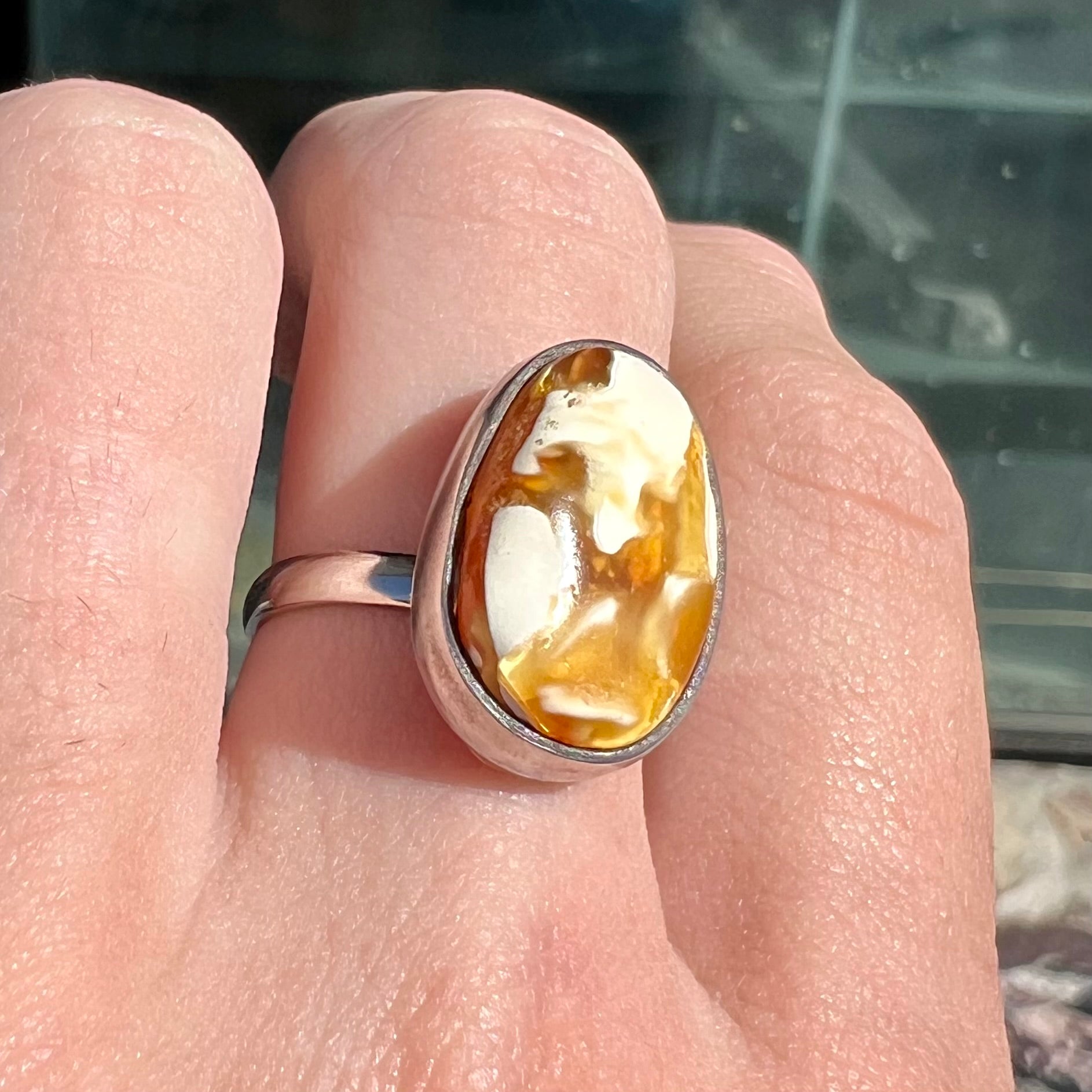 An adjustable sterling silver solitaire ring set with a cabochon cut butterscotch amber stone.