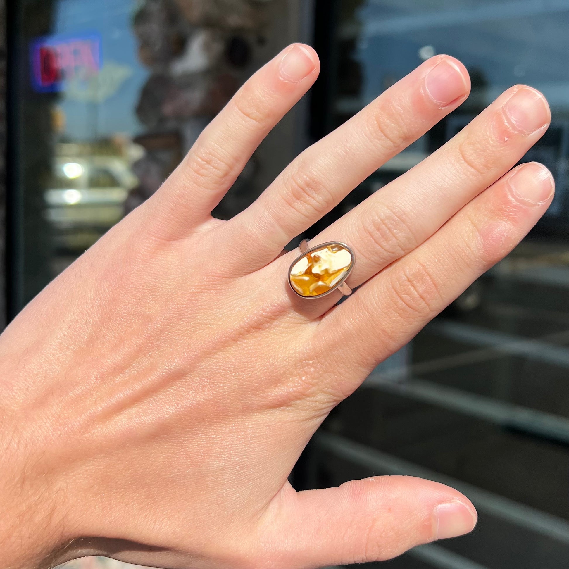 An adjustable sterling silver solitaire ring set with a cabochon cut butterscotch amber stone.