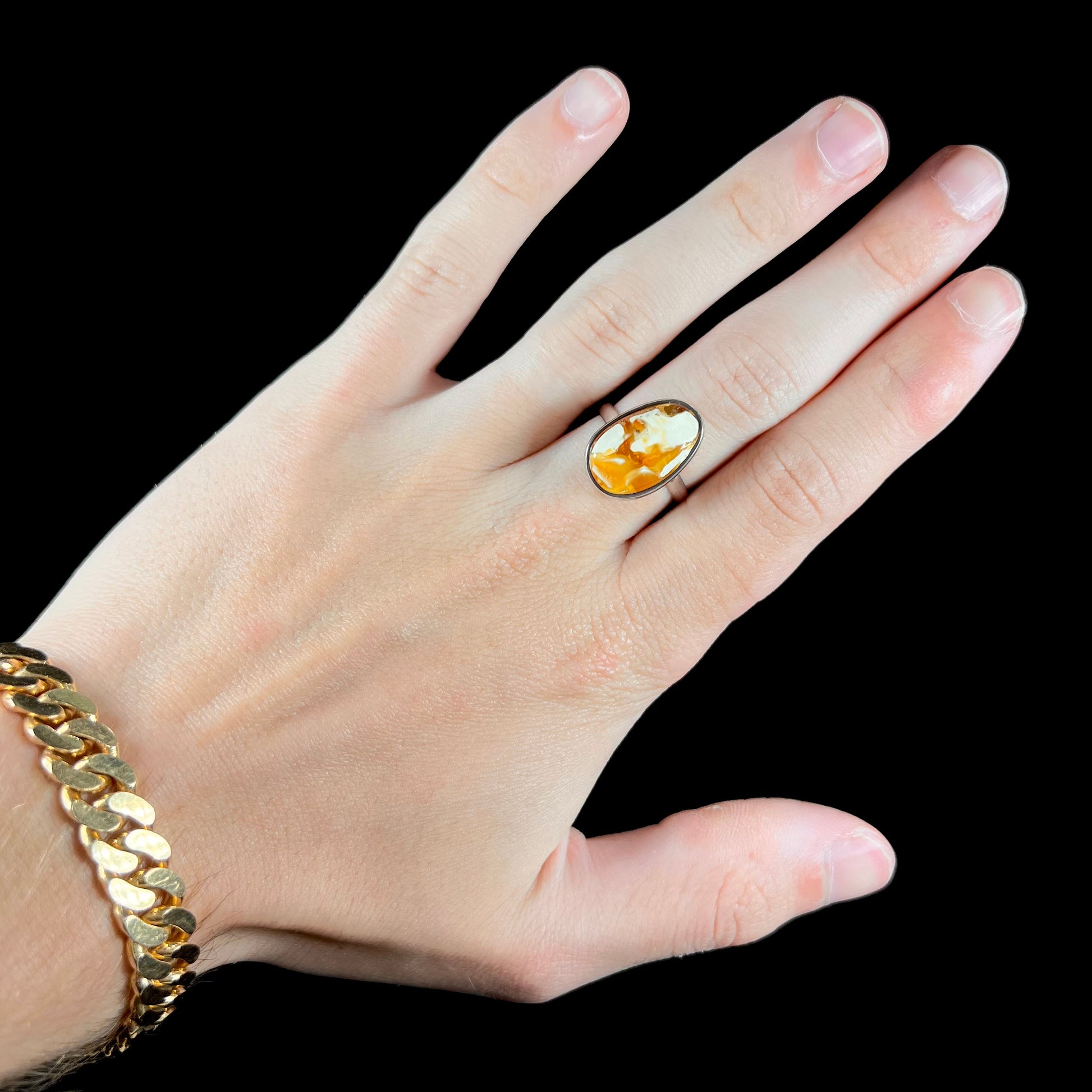 An adjustable sterling silver solitaire ring set with a cabochon cut butterscotch amber stone.