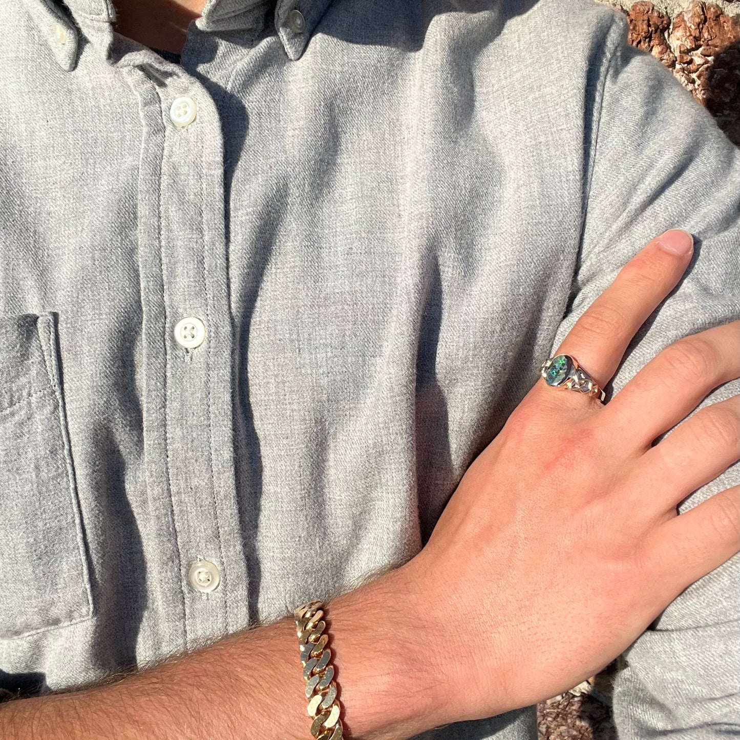 A unisex Celtic style natural boulder opal ring cast in yellow gold. The opal shines green and blue.
