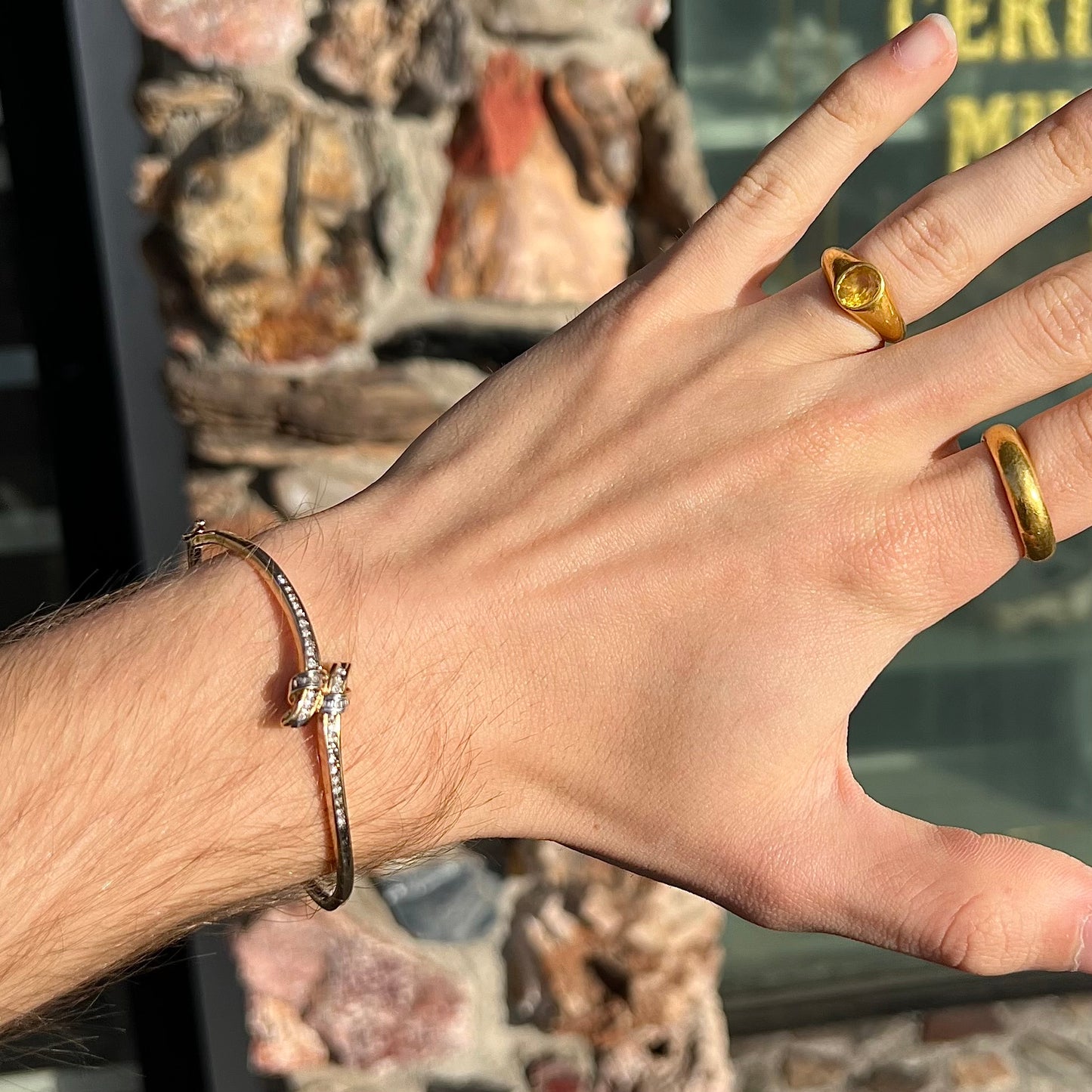 A ladies' knot style yellow gold bangle bracelet set with round and baguette cut diamonds.