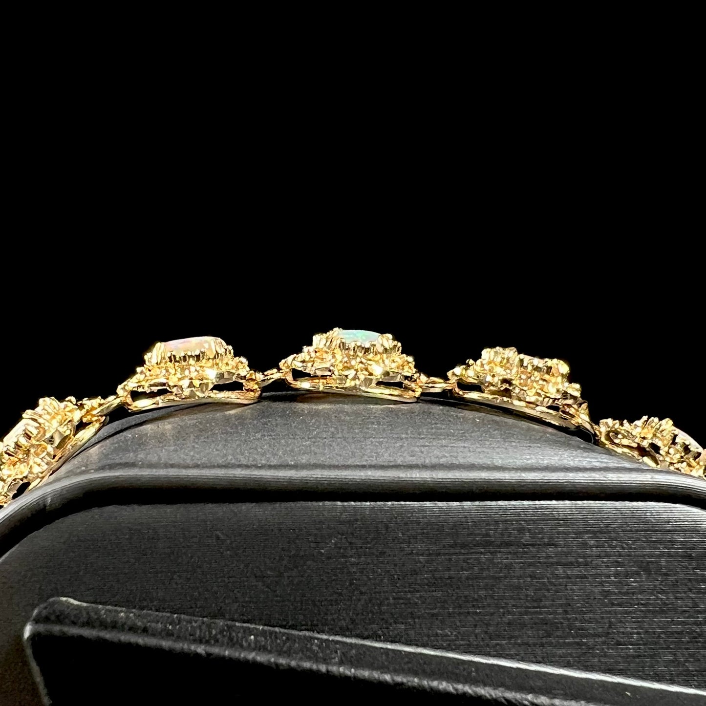 A ladies' yellow gold bracelet set with natural, oval cabochon cut white crystal opals.