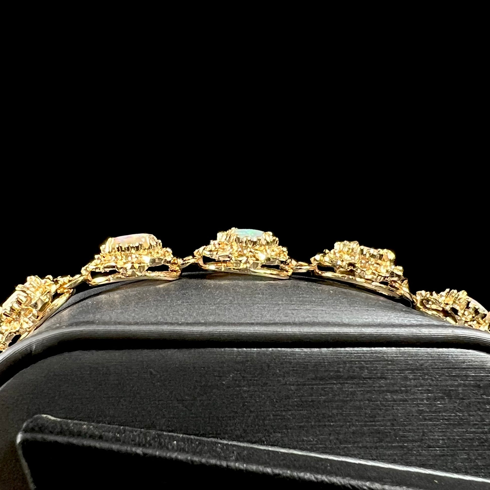 A ladies' yellow gold bracelet set with natural, oval cabochon cut white crystal opals.