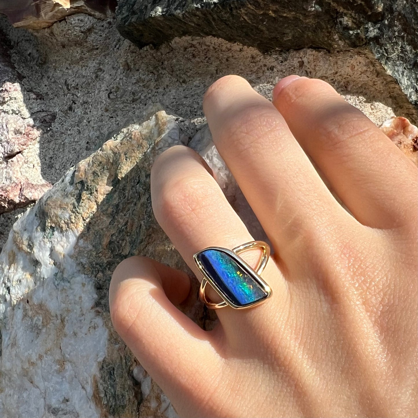 A ladies' split shank gold ring bezel set with a natural, Australian black boulder opal.