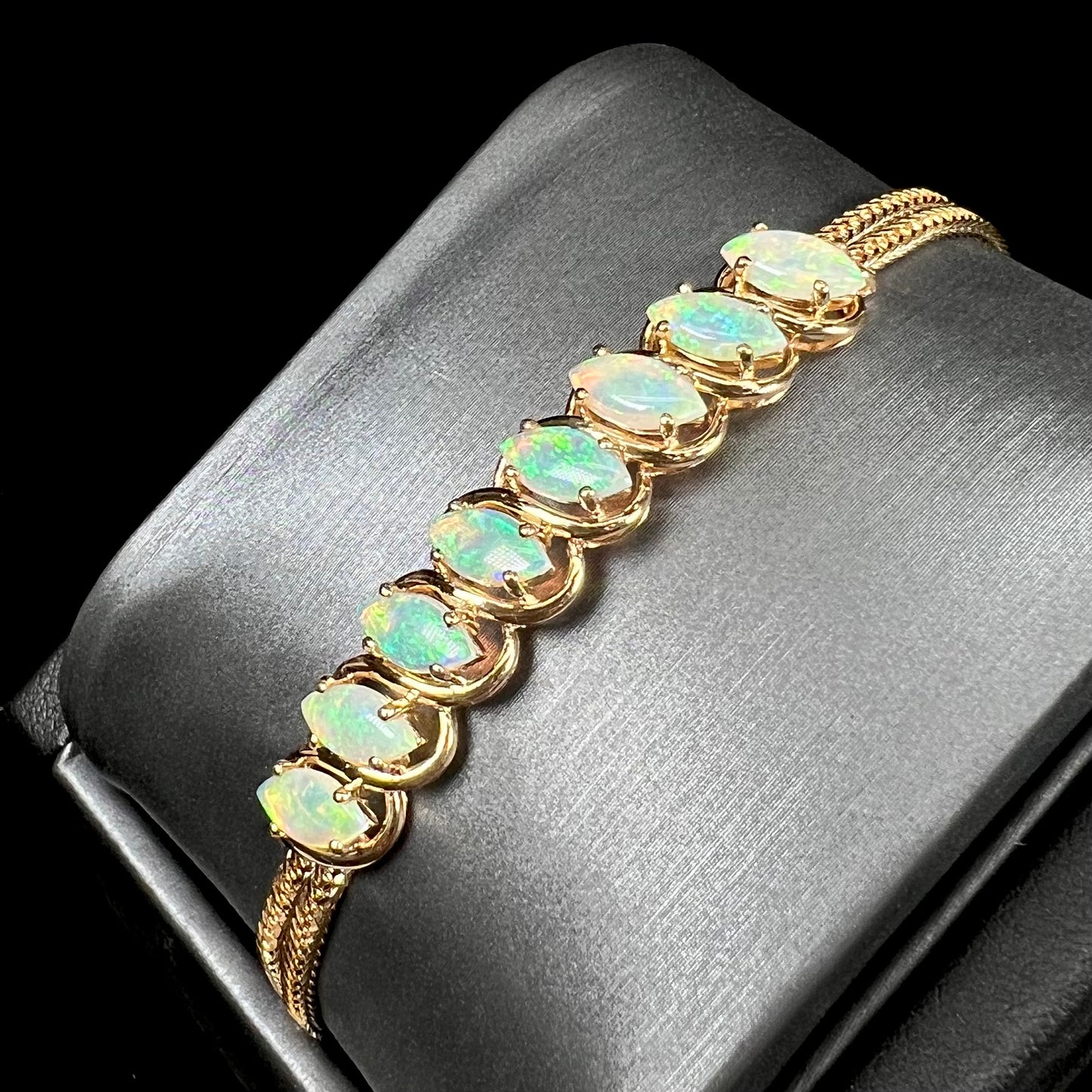 A ladies' yellow gold bracelet prong set with eight natural, marquise cabochon cut opals.
