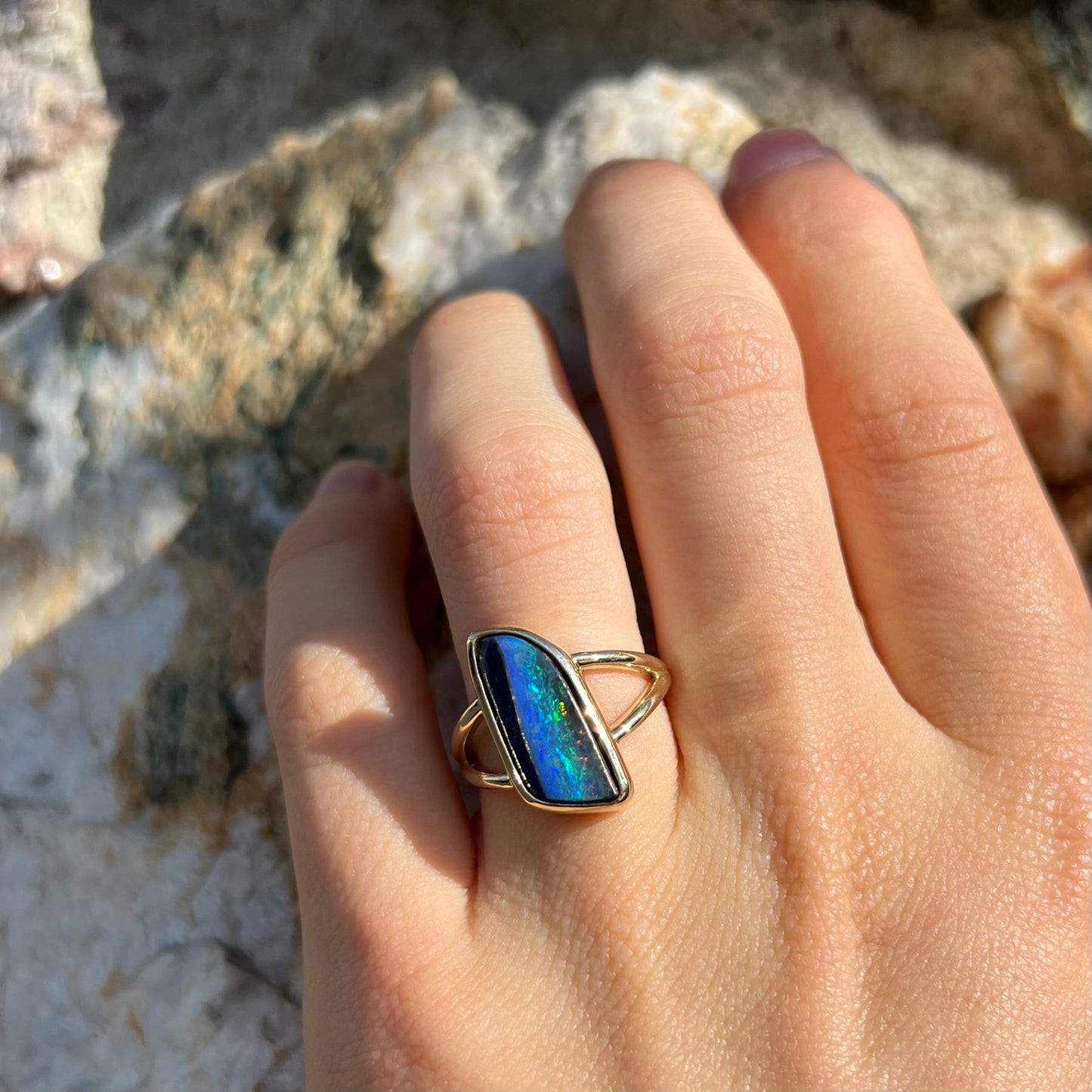 A ladies' split shank gold ring bezel set with a natural, Australian black boulder opal.