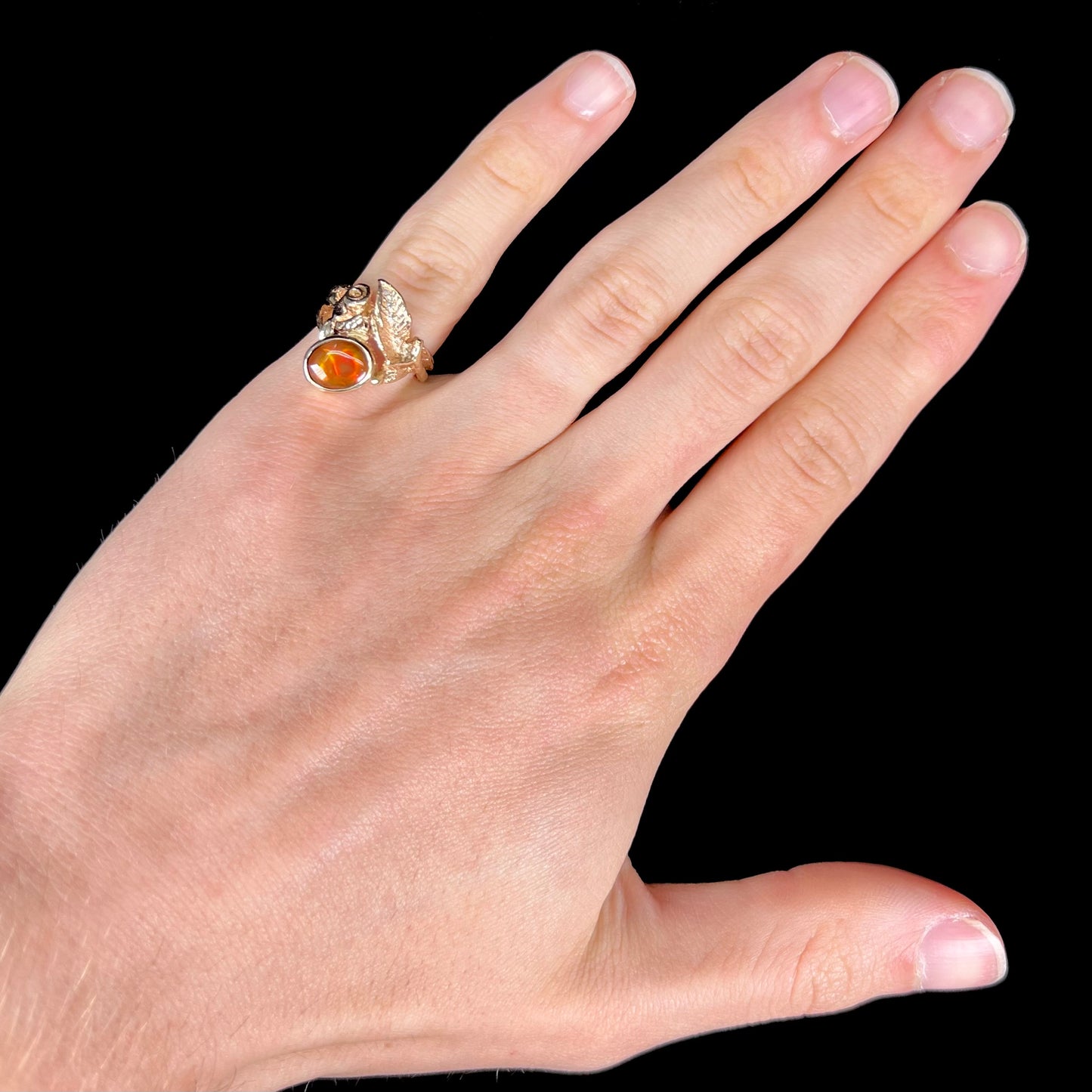 A ladies' yellow gold flower style ring set with an oval cabochon cut fire agate and diamond accents.