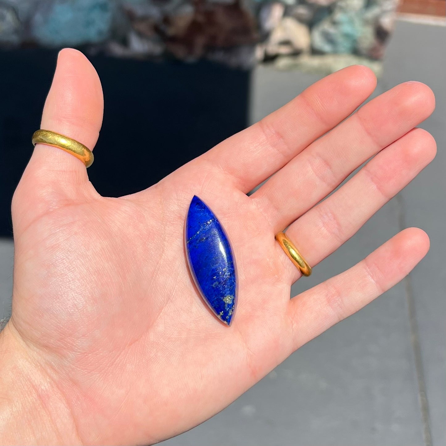 A loose, marquise cabochon cut lapis lazuli stone. The stone has pyrite inclusions.