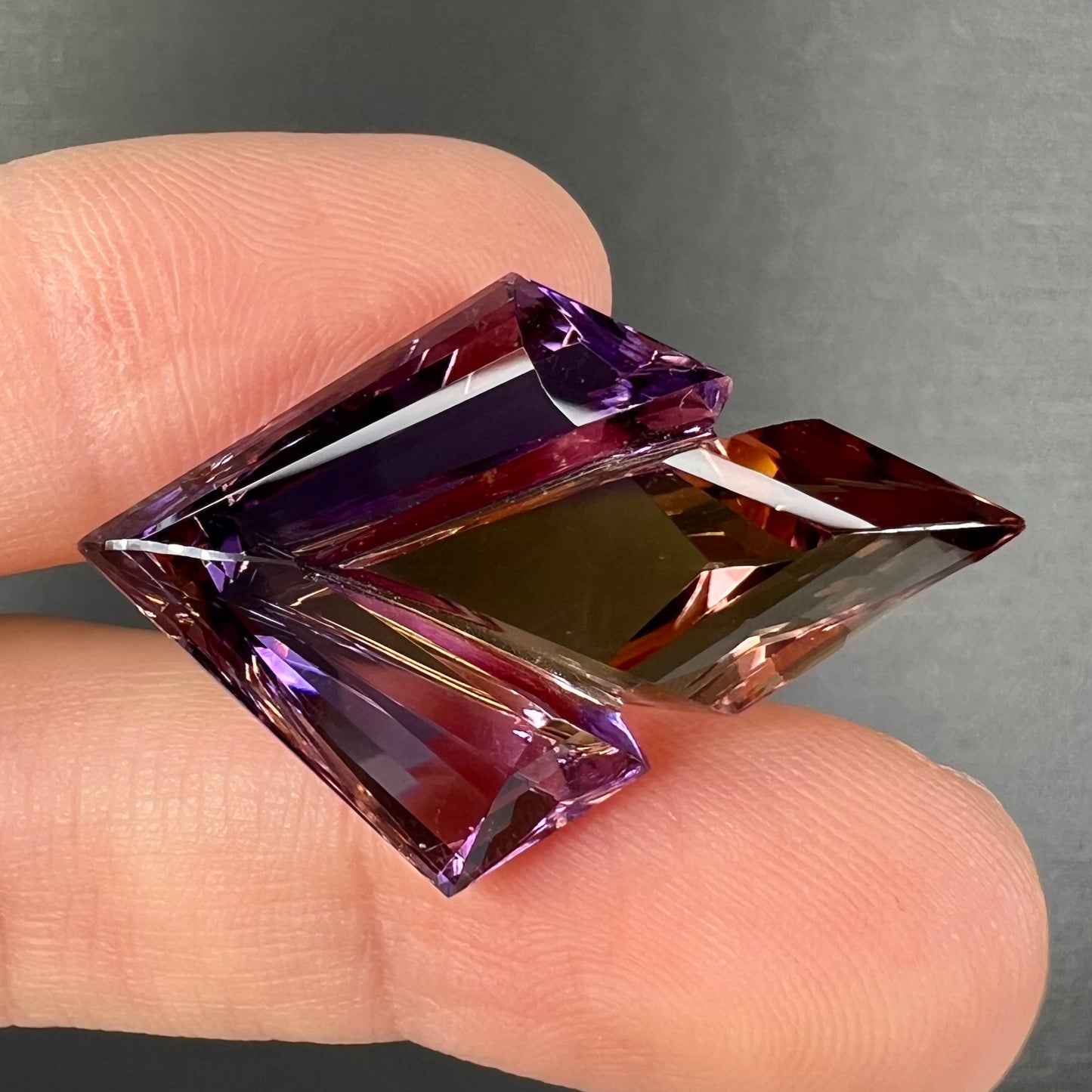 A loose, faceted fantasy cut ametrine gemstone cut by famous carver, Arthur Lee Anderson.