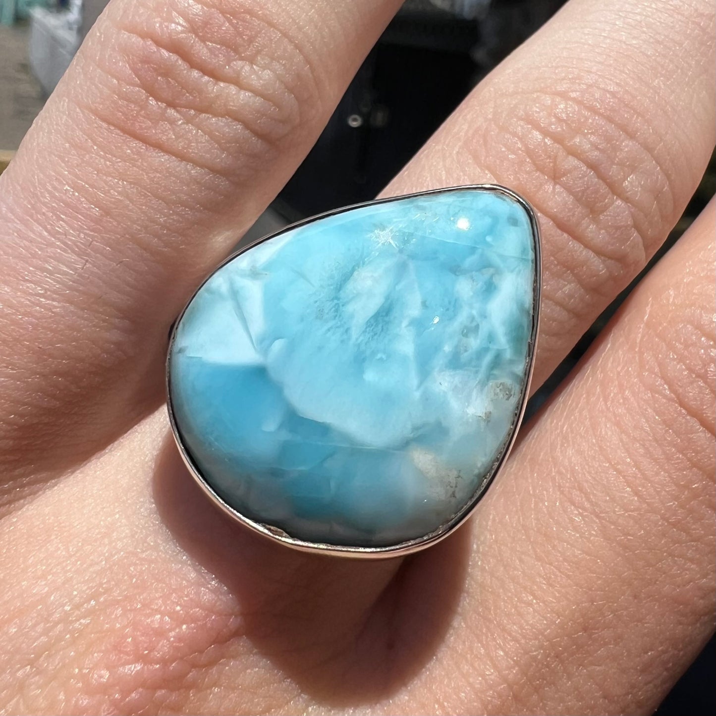 A ladies' large, pear shaped larimar solitaire ring in sterling silver. The larimar stone measures an inch long.
