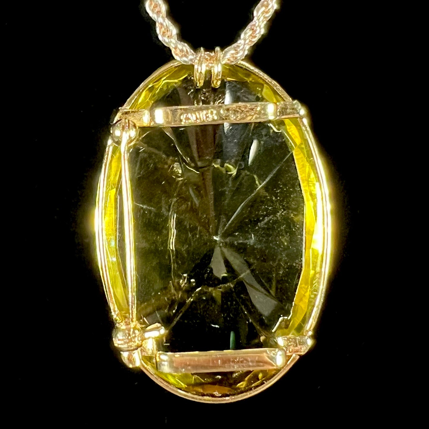 A faceted oval cut lemon quartz gemstone pendant in gold plated sterling silver. The quartz is a green-yellow color.