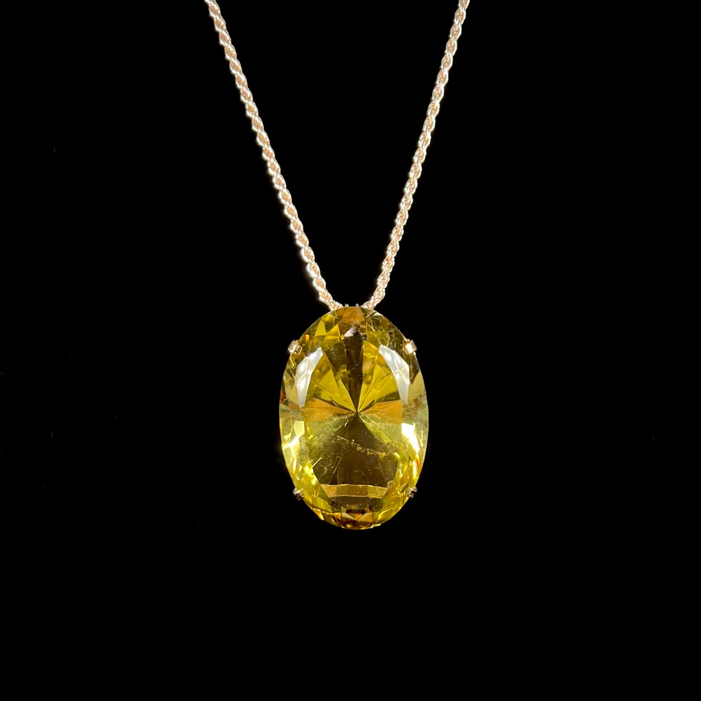 A faceted oval cut lemon quartz gemstone pendant in gold plated sterling silver. The quartz is a green-yellow color.