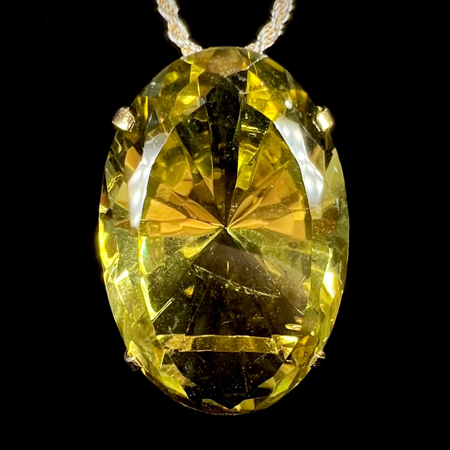 A faceted oval cut lemon quartz gemstone pendant in gold plated sterling silver. The quartz is a green-yellow color.