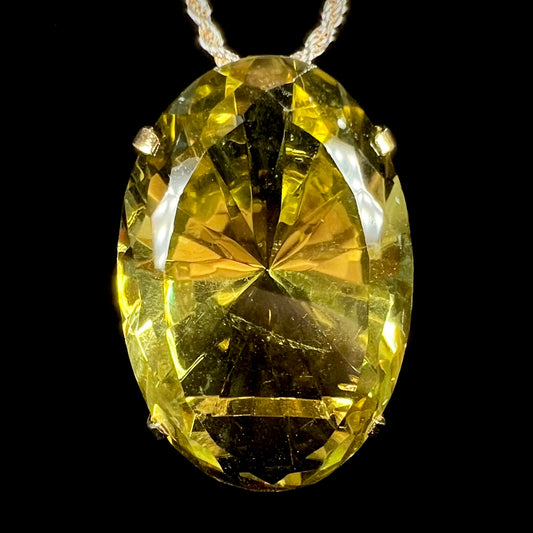 A faceted oval cut lemon quartz gemstone pendant in gold plated sterling silver.  The quartz is a green-yellow color.
