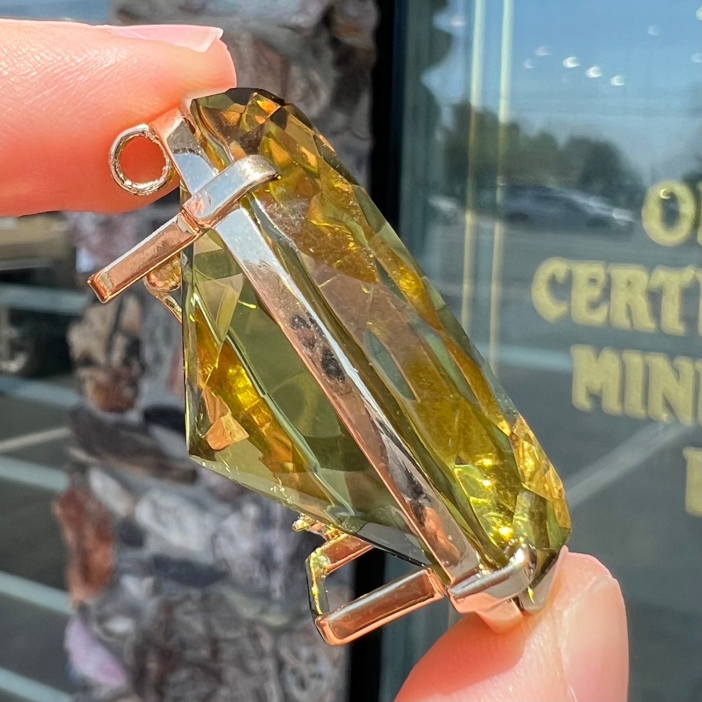 A faceted oval cut lemon quartz gemstone pendant in gold plated sterling silver. The quartz is a green-yellow color.