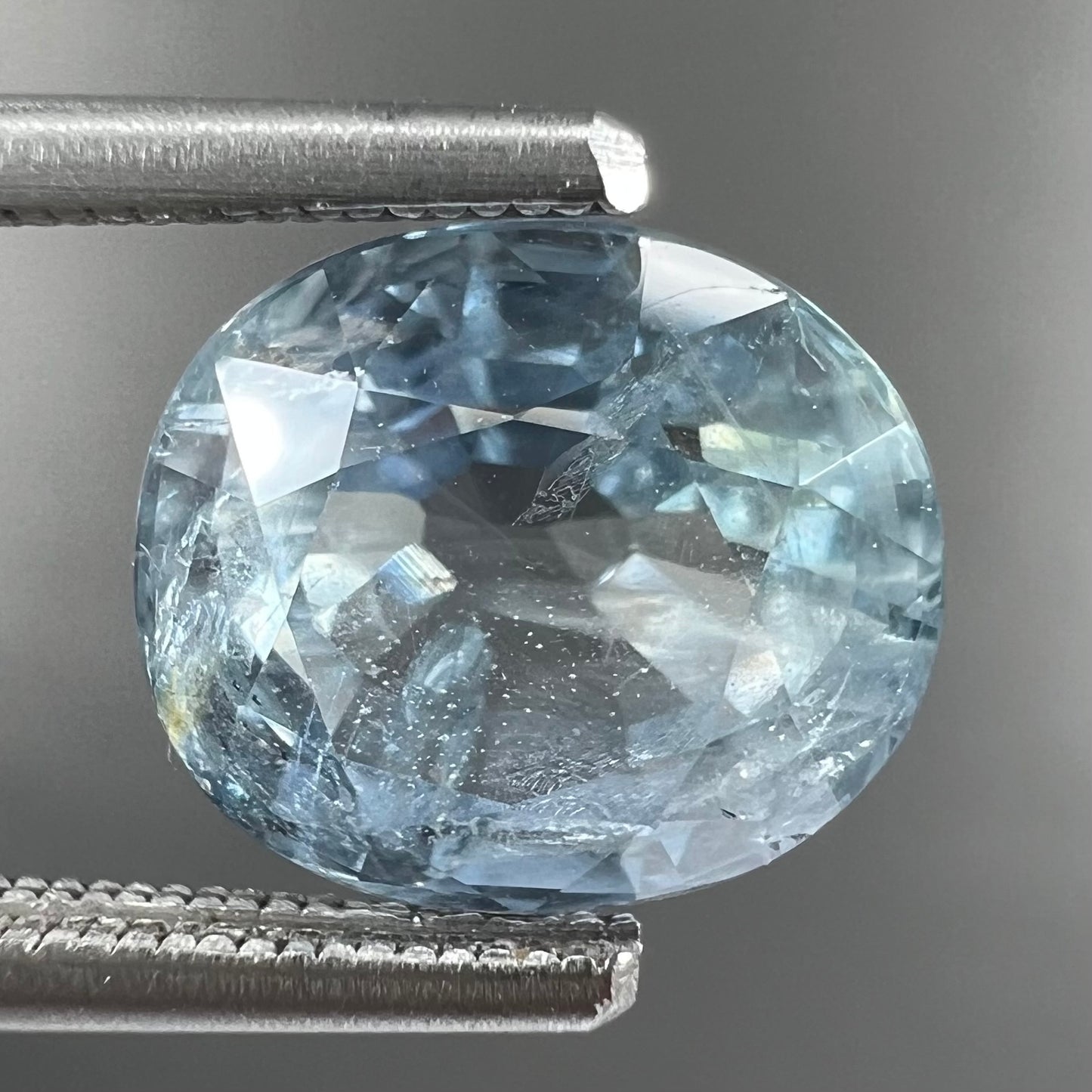 A loose, faceted oval cut light blue natural sapphire gemstone.