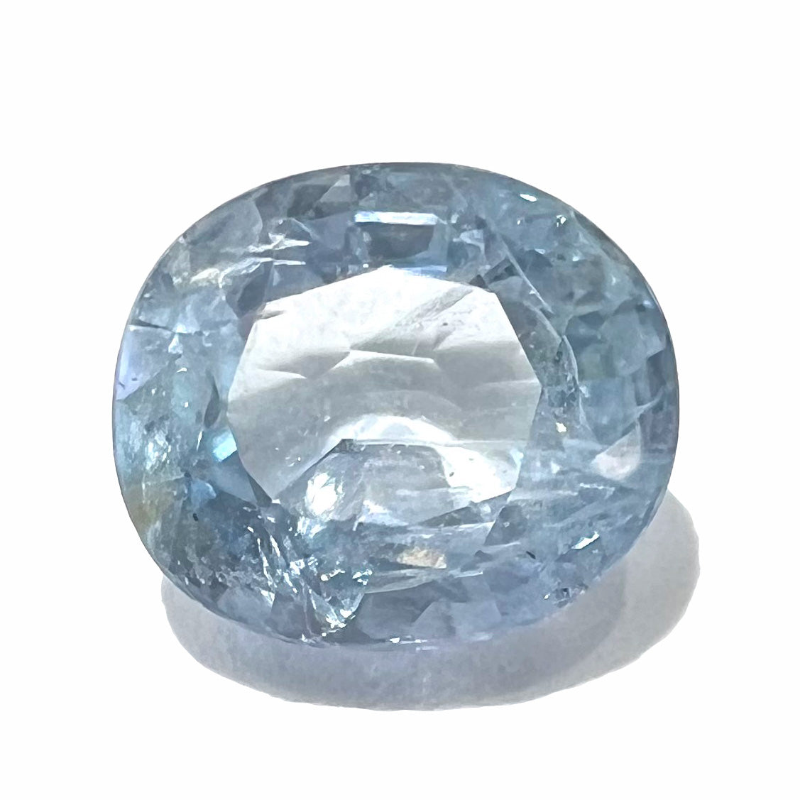 A loose, faceted oval cut light blue natural sapphire gemstone.