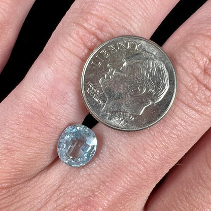A loose, faceted oval cut light blue natural sapphire gemstone.