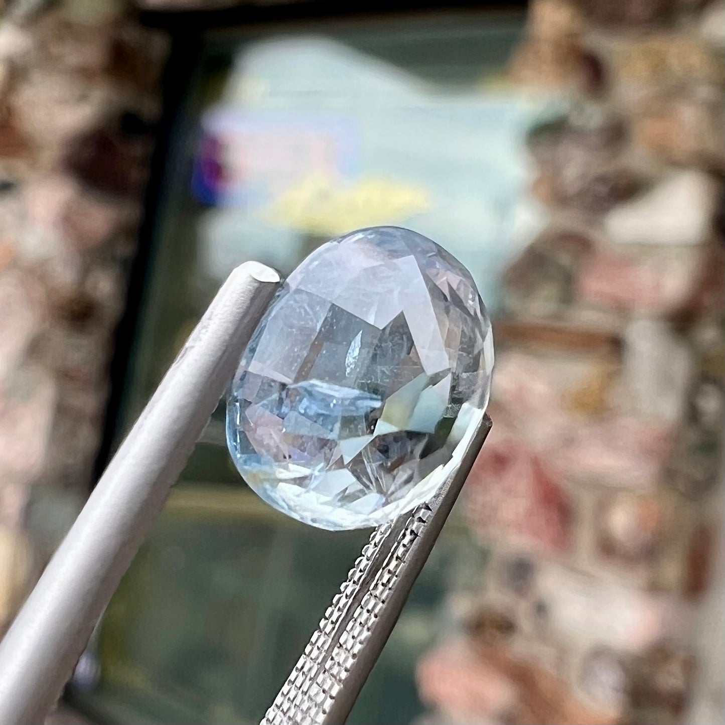 A loose, faceted oval cut light blue natural sapphire gemstone.