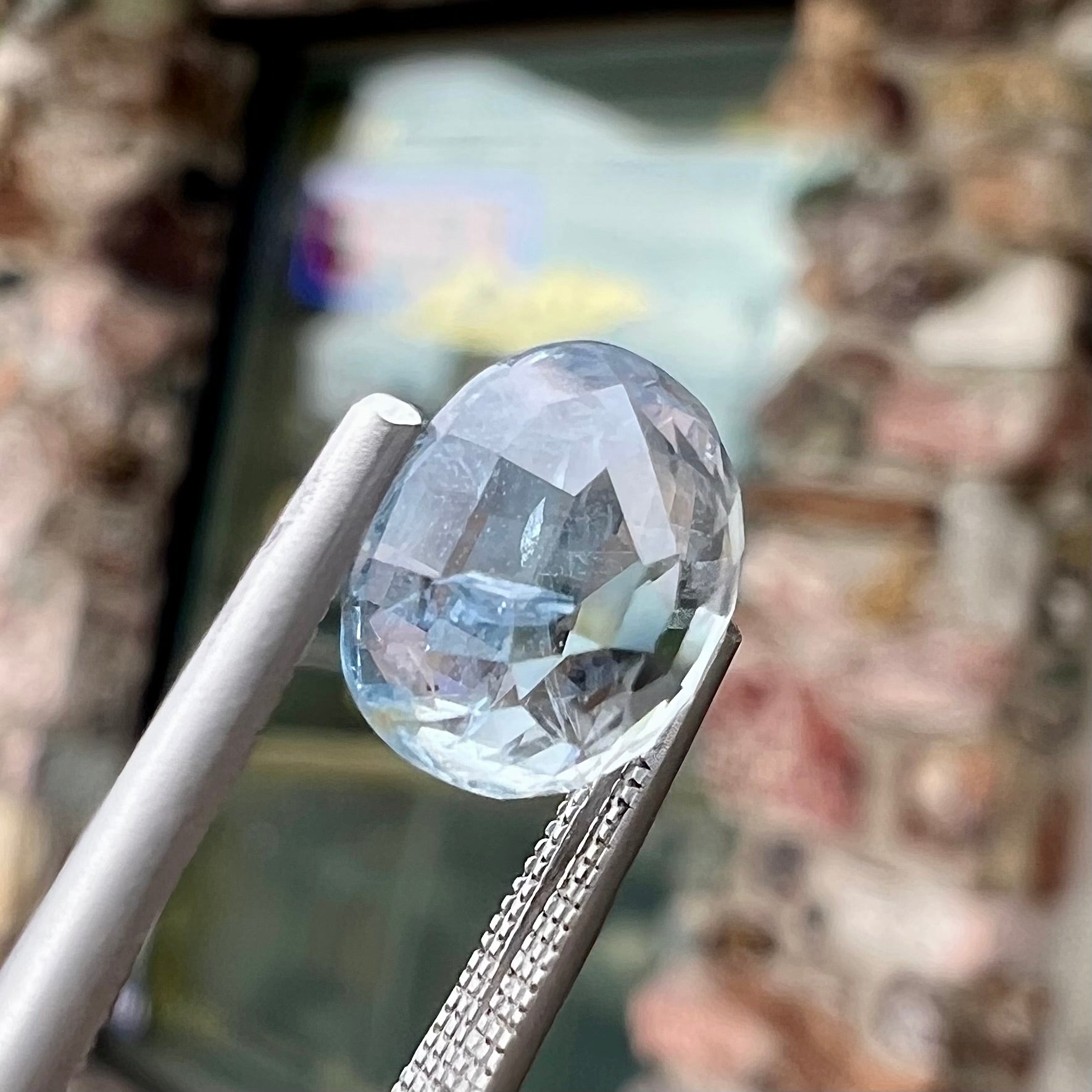 A loose, faceted oval cut light blue natural sapphire gemstone.