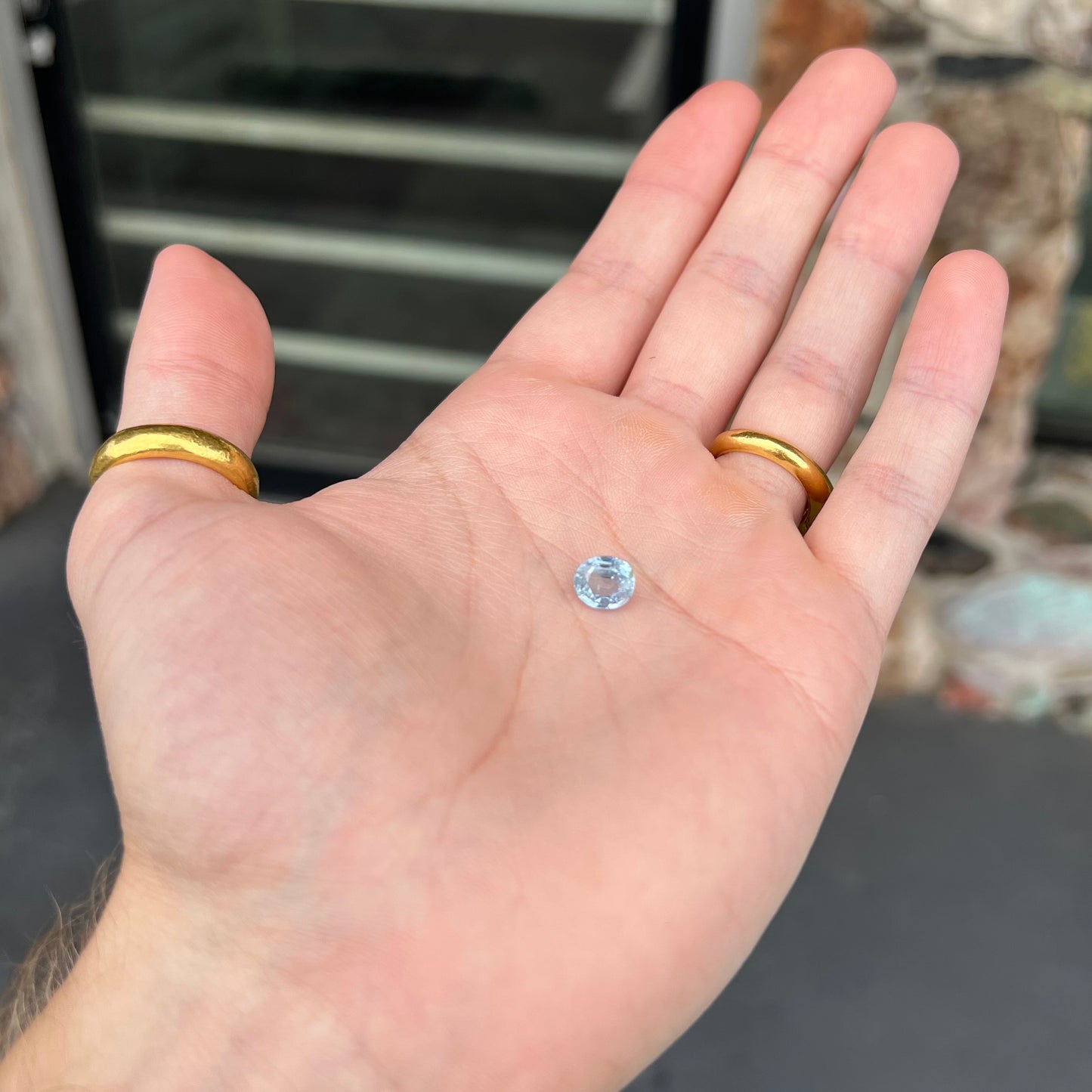 A loose, faceted oval cut light blue natural sapphire gemstone.