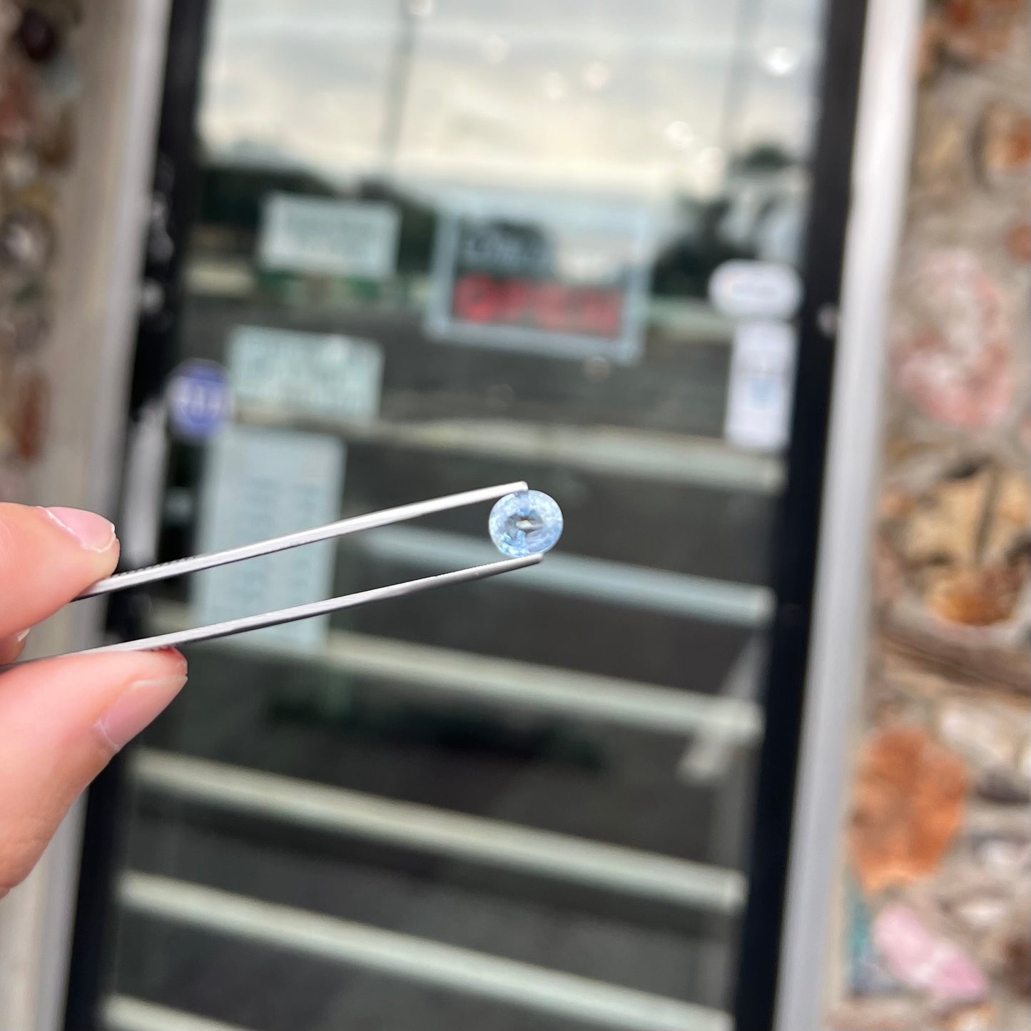 A loose, faceted oval cut light blue natural sapphire gemstone.