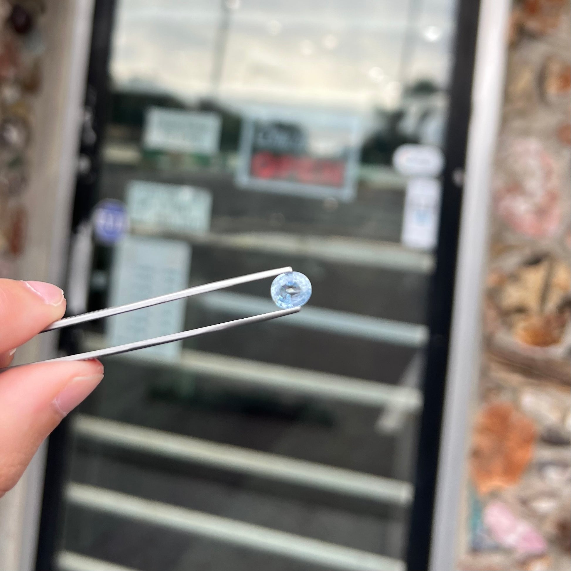 A loose, faceted oval cut light blue natural sapphire gemstone.