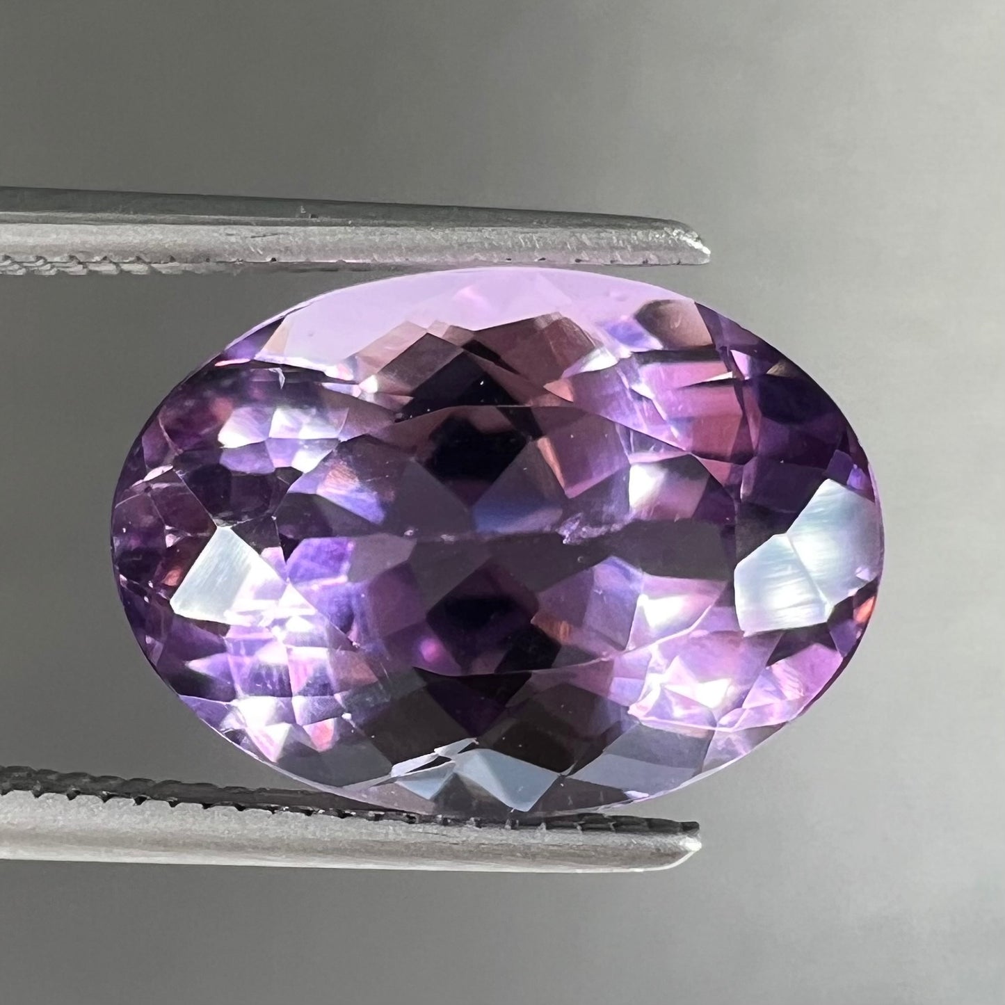 A faceted oval cut amethyst gemstone. The stone is a light purple color.