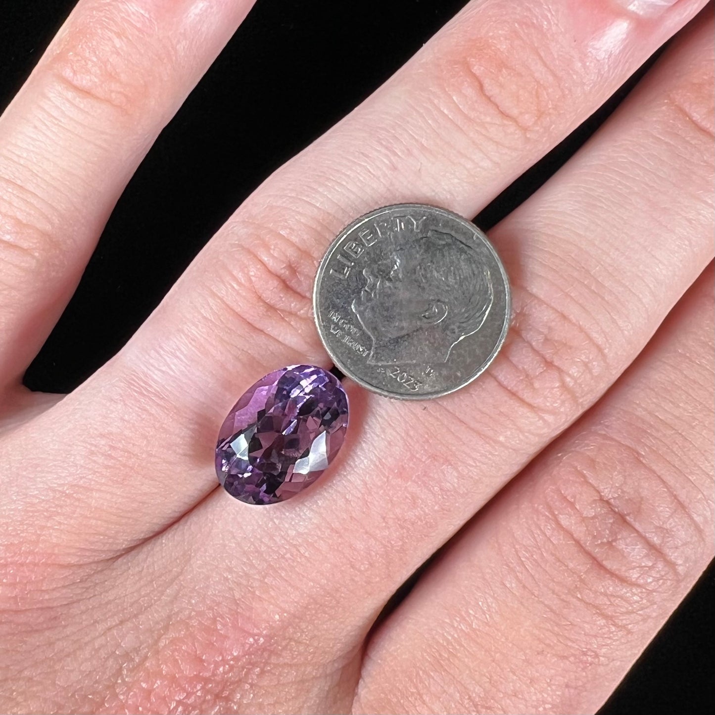 A faceted oval cut amethyst gemstone. The stone is a light purple color.