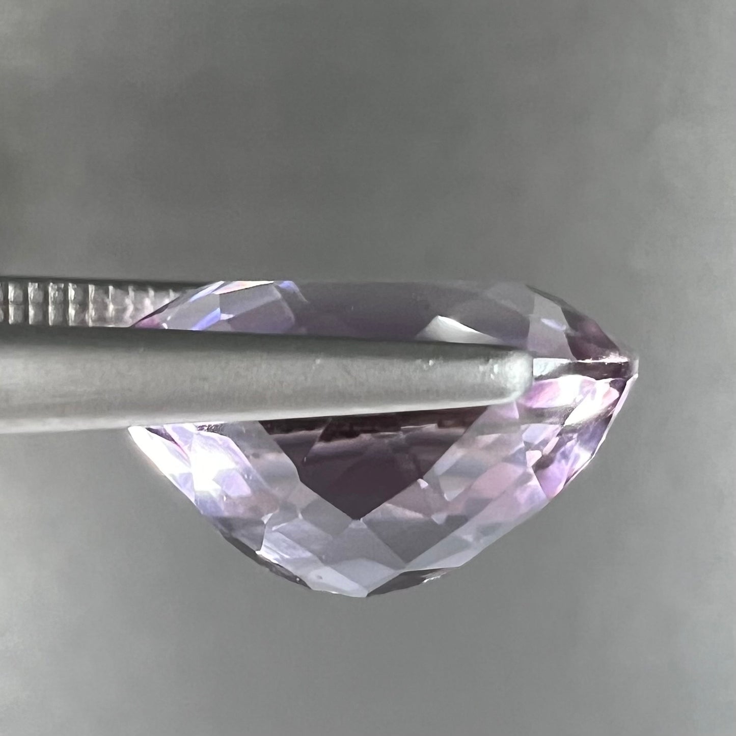 A faceted oval cut amethyst gemstone. The stone is a light purple color.