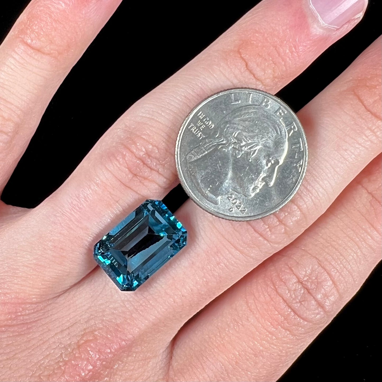 A loose, emerald cut London blue topaz gemstone. The stone is a deep, dark blue color.