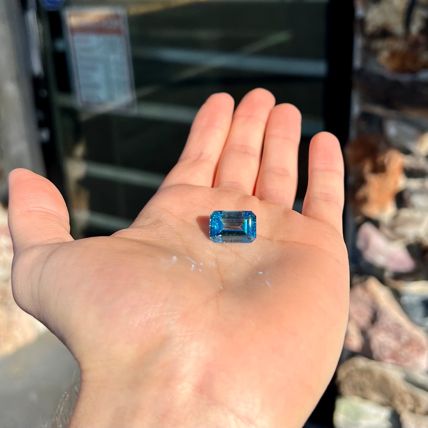 A loose, emerald cut London blue topaz gemstone. The stone is a deep, dark blue color.