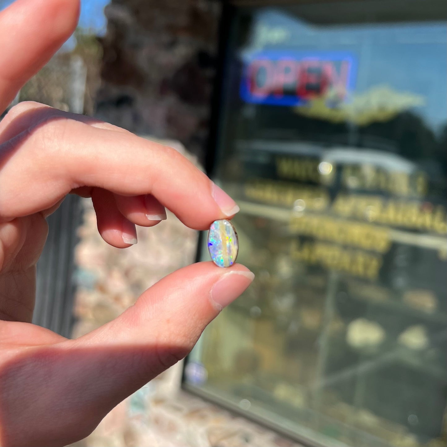 An oval cabochon cut boulder opal from Quilpie, Australia. The opal has multicolor color play.