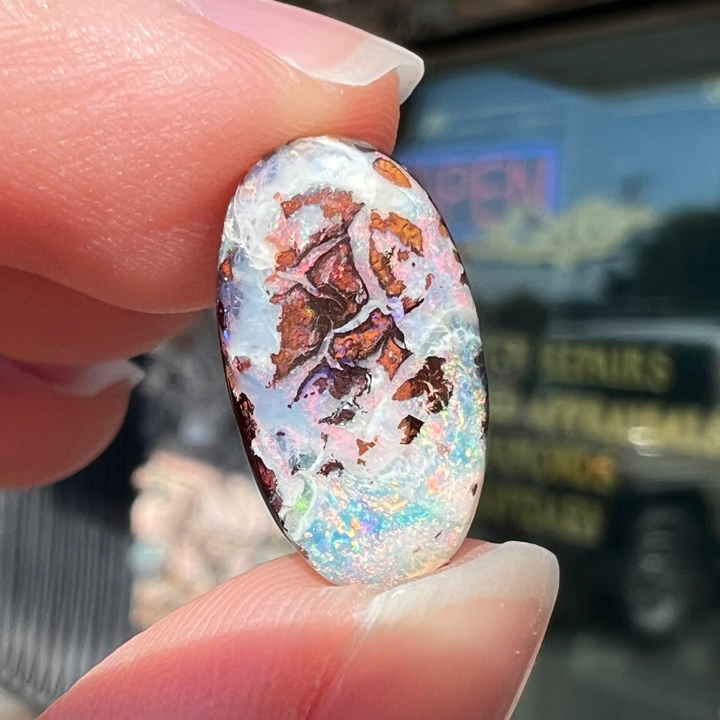 An oval cabochon cut boulder opal stone from Koroit, Australia. The opal has a white body tone.
