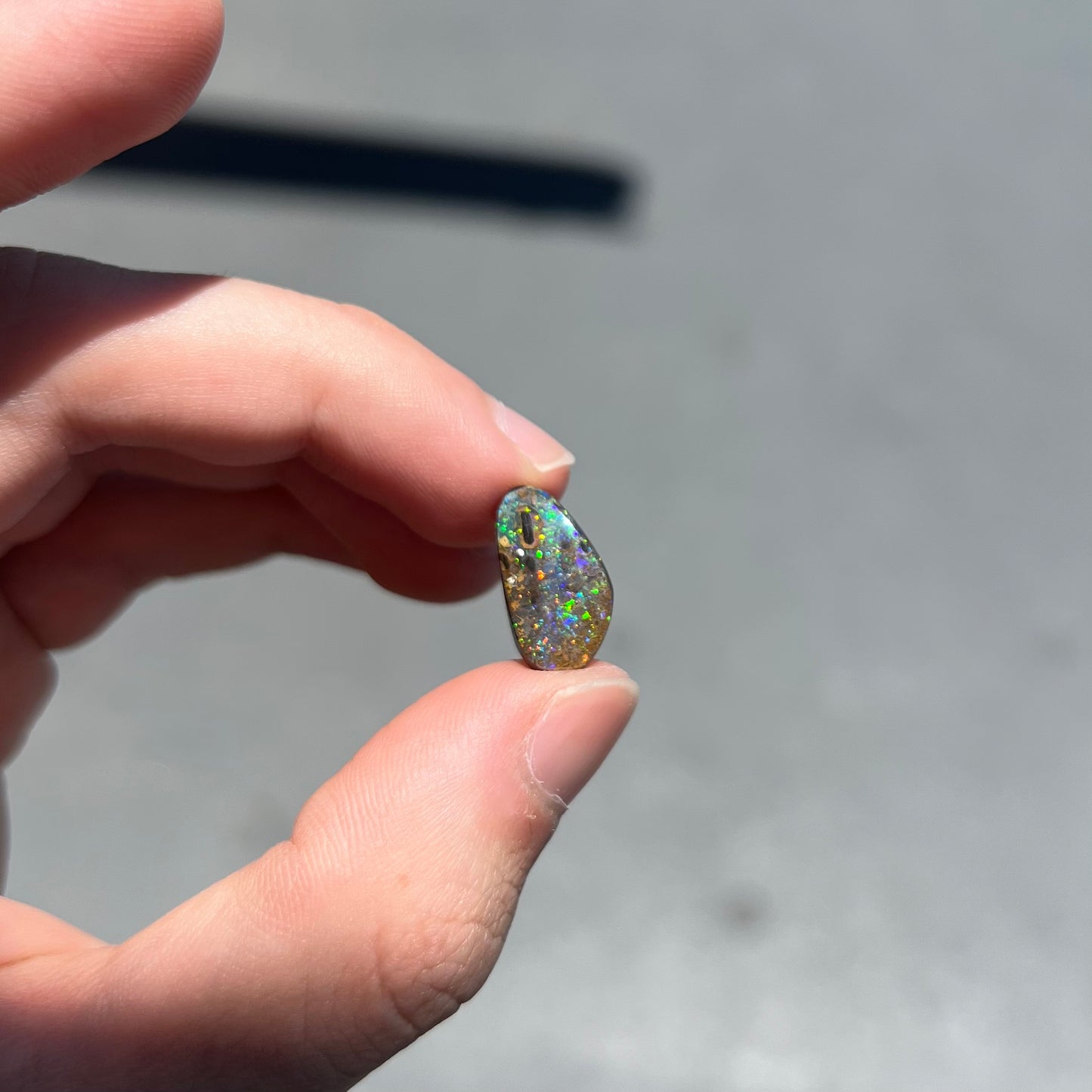 A loose boulder opal stone from Quilpie, Australia. The opal shines colors of green and orange.
