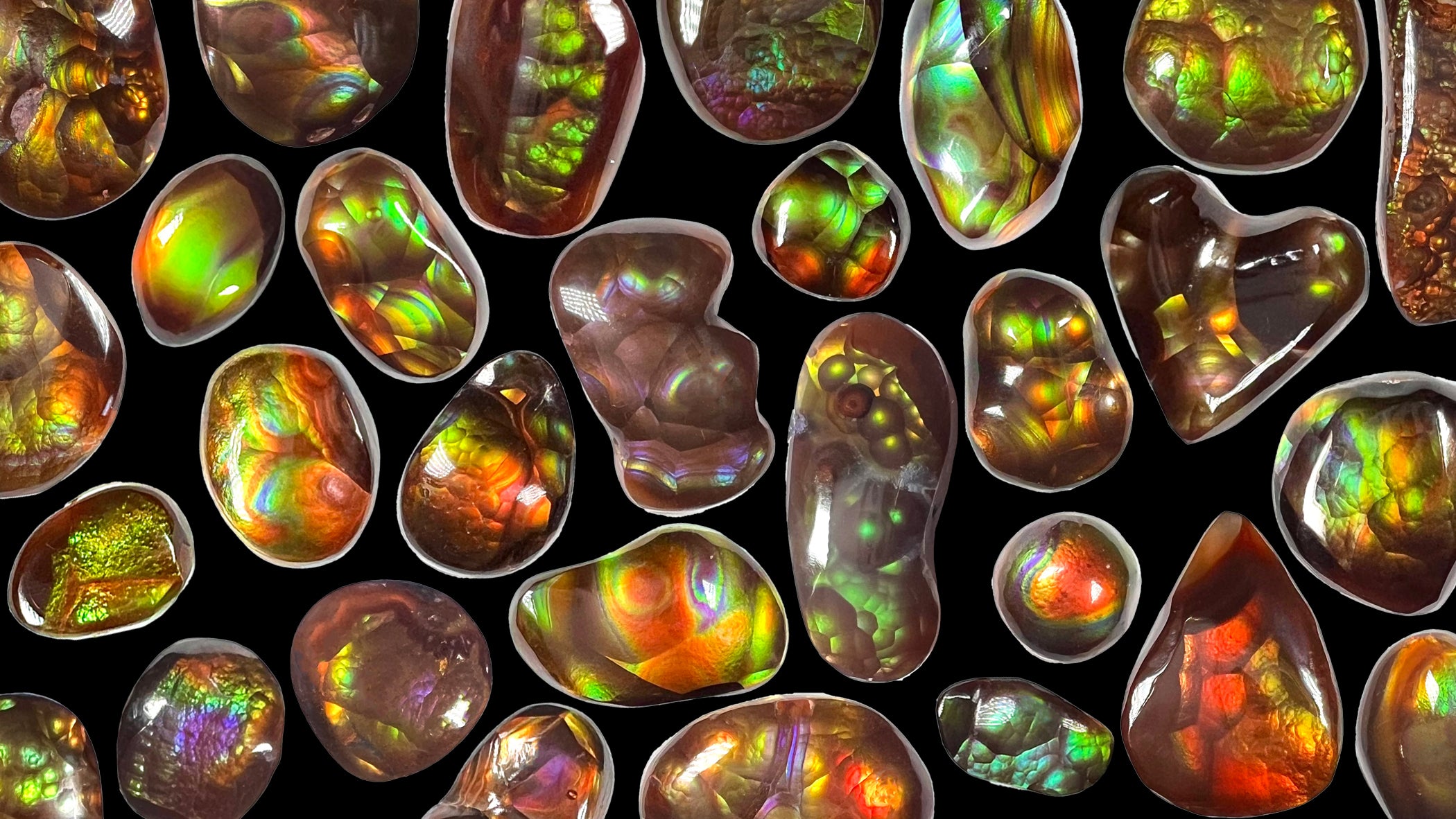 A variety of colorful Mexican fire agate cabochons arranged on a black background.